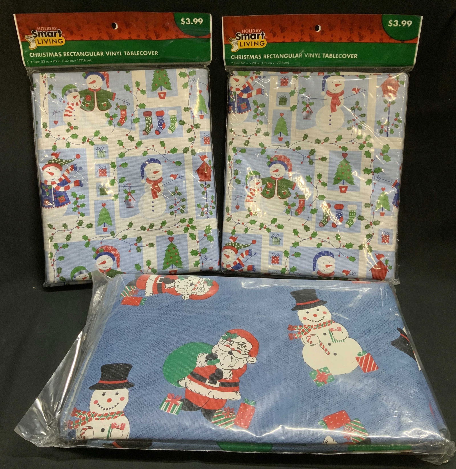 Lt3 Christmas Vinyl Table Covers HOLIDAYSMART NIP: Lot includes, 2 Holiday Smart Living Christmas rectangular vinyl table cover size 52in x 70in (new in plastic), & 1 Santa with snowman motifs cover. Has not been removed out of plastic. Sold as