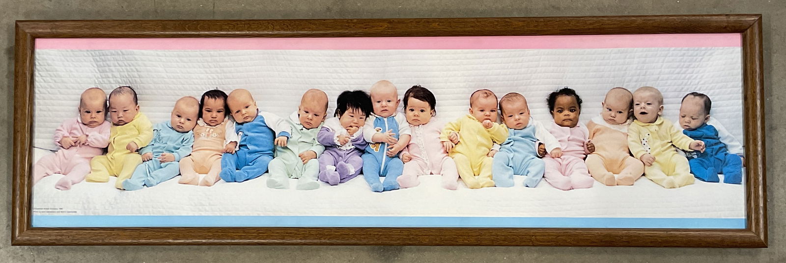 Framed Campanaro Baby Portrait Print 1985 41in: Framed print. Portrait of babies. Photograph by Sam Campanaro and Martin Czamanske. Copyright Eastman Kodak 1985. Wood frame. Not examined out of frame. Frame measures approx. 12.5 x 41 inches.