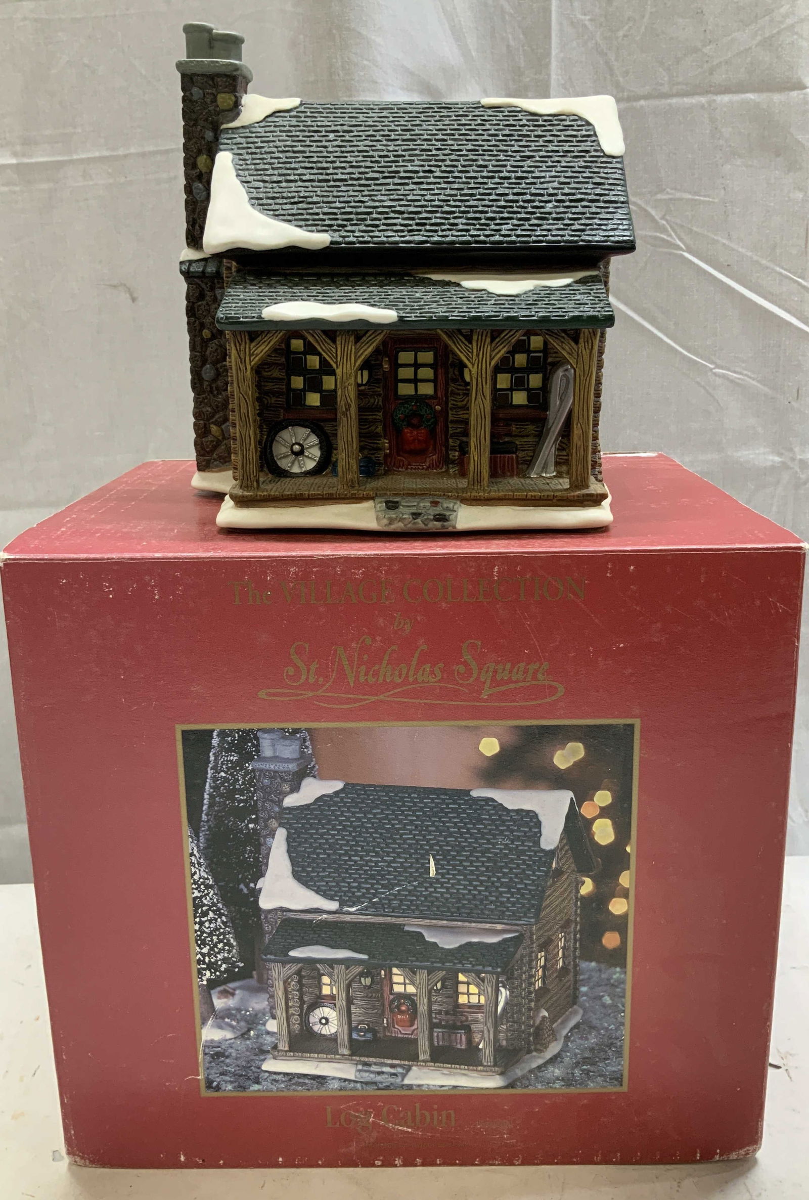 1998 Village Collection By St. Nicholas Square Bx: The Village Collection by St. Nicholas Square. Log cabin features hand painted accents & is porcelain material. Has not been tested for function, lot is sold as is. Comes with original box. Surface we