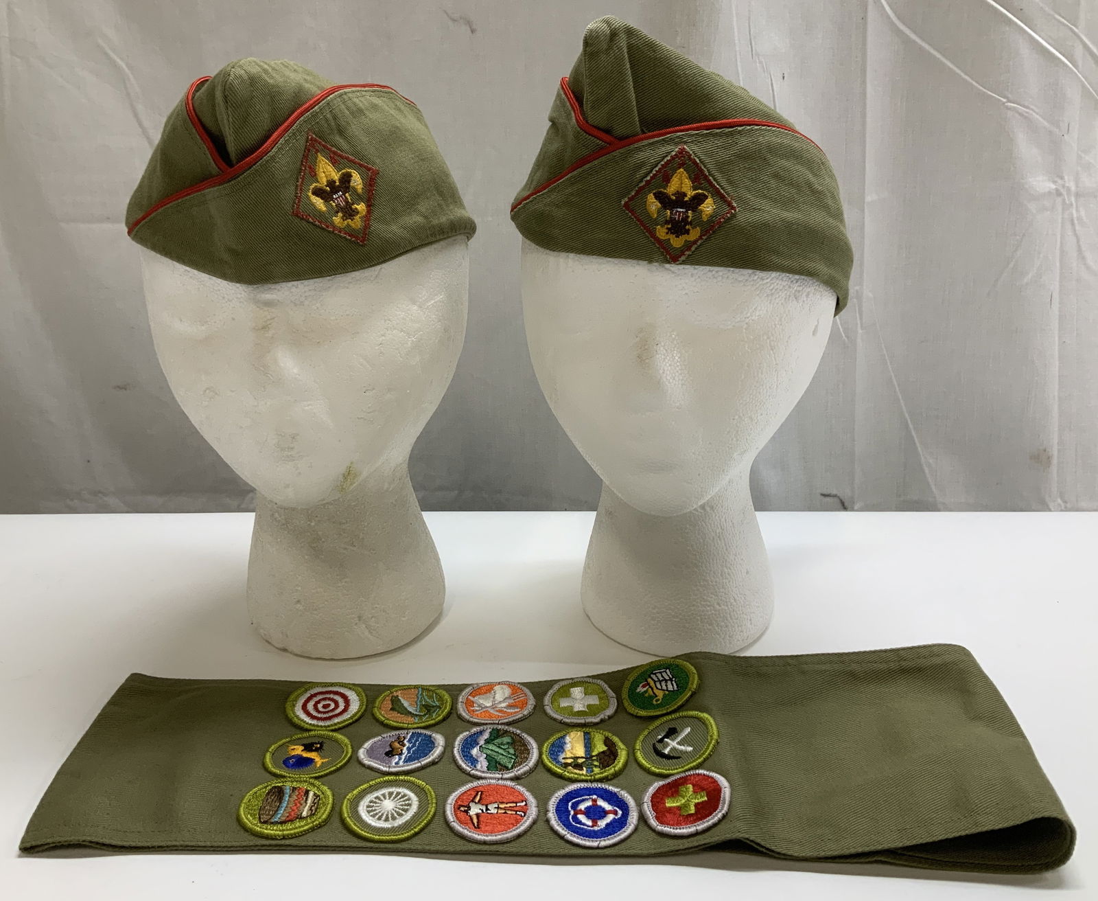 Lot 3 Vtg Boy Scouts Uniform Caps & Sash: Lot includes, 2 Boy Scouts of America (BSA) official garrison uniform caps featuring a diamond-shaped emblem patch. Lot also includes, 1 Boy Scouts of America (BSA) merit badge sash decorated with mul