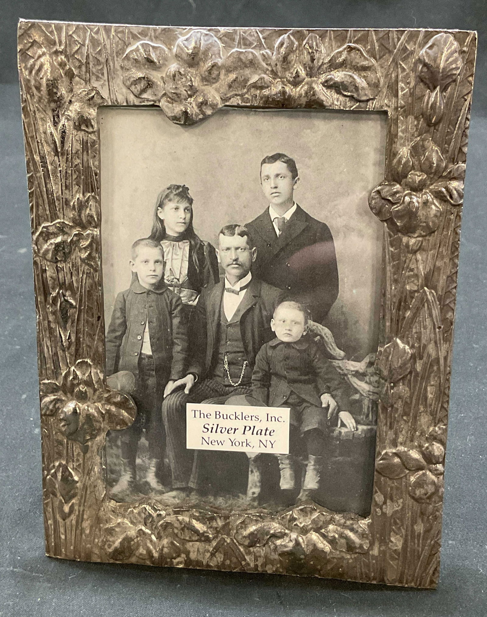 Bucklers Inc Silver Plated Picture Frame USA: The Bucklers Inc silver plated picture frame. Reads The Bucklers Inc Silver Plate New York, NY. Embossed floral motif pattern. Rectangular shape. Measures approx 4.5 x 6.5 inches. Surface wear consist
