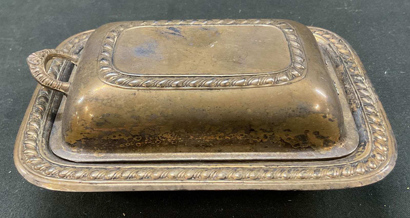 Vintage Silver Plated Lidded Butter Dish: Vintage silver plated lidded butter dish. Round dish with ribbed border. Handle on lid with ribbed surface. Ribbed pattern on lid. Ornate scroll motif. Measures approx 3.5 x 4.5 x 2 inches. Some scrat