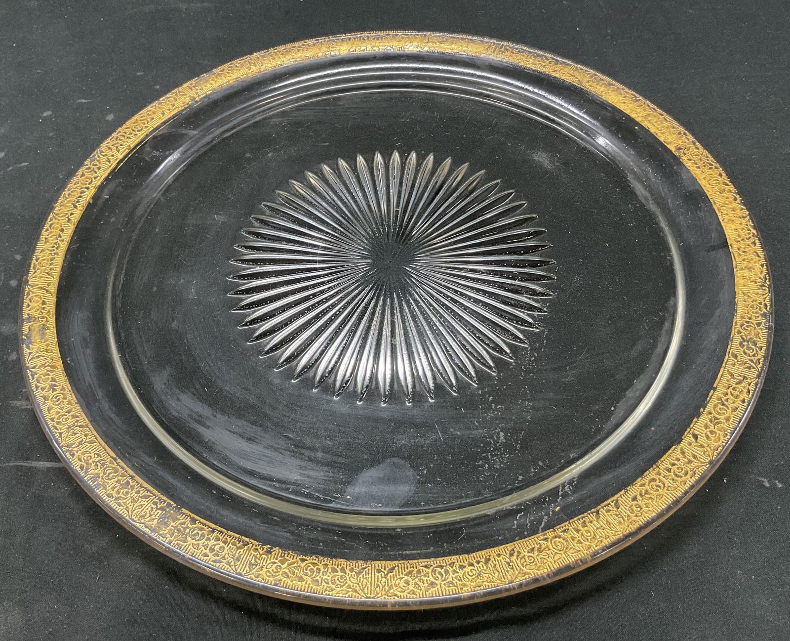 Vintage Glass Gilt Rim Serving Platter: Vintage glass gilt rim serving platter. Round platter. Starburst design in center. Gilt embossed rim with floral and scroll motifs. Measures approx 12.5 inches in diameter. Some scratching. Serving pl