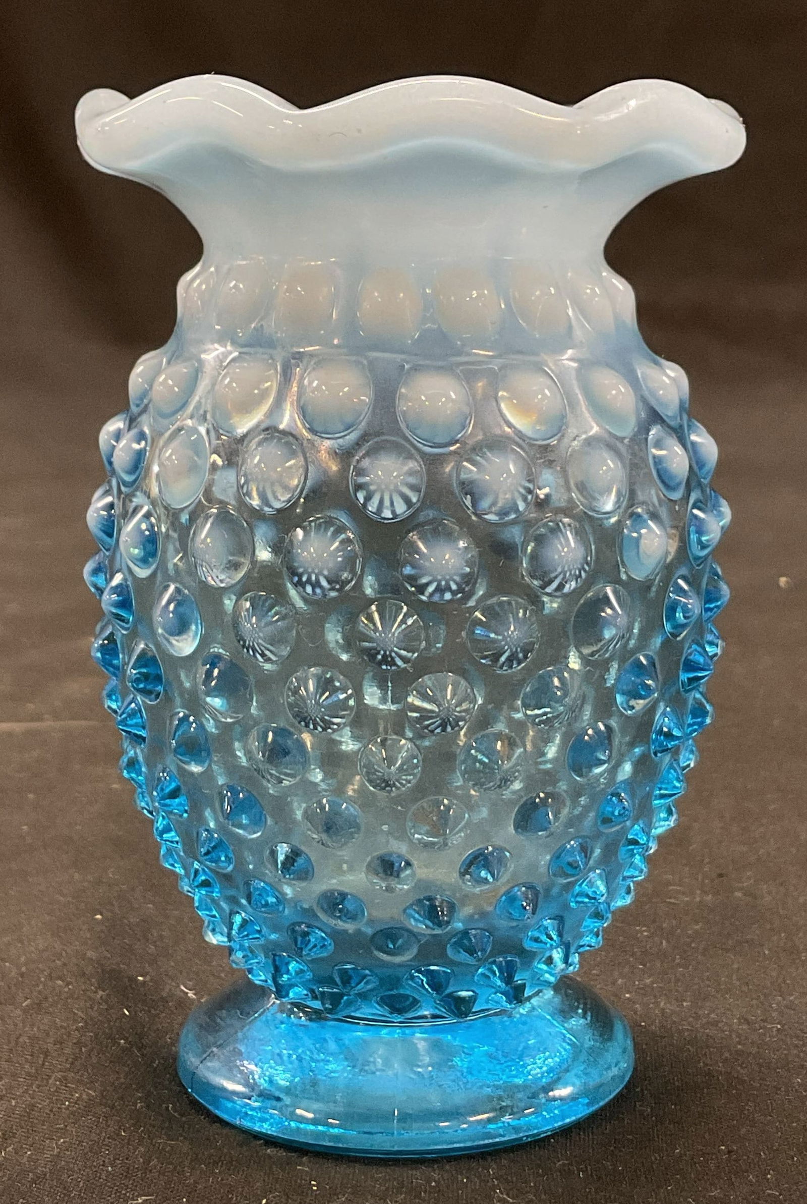 Blue Art Glass Hobnail Ruffled Bud Vase: Blue handblown art glass hobnail ruffled bud vase. Hobnail pattern. Ruffled and scalloped edge. Round pedestal base. Bulbous body. Detailed features and textures. Measures ht approx 3.5 inches base di