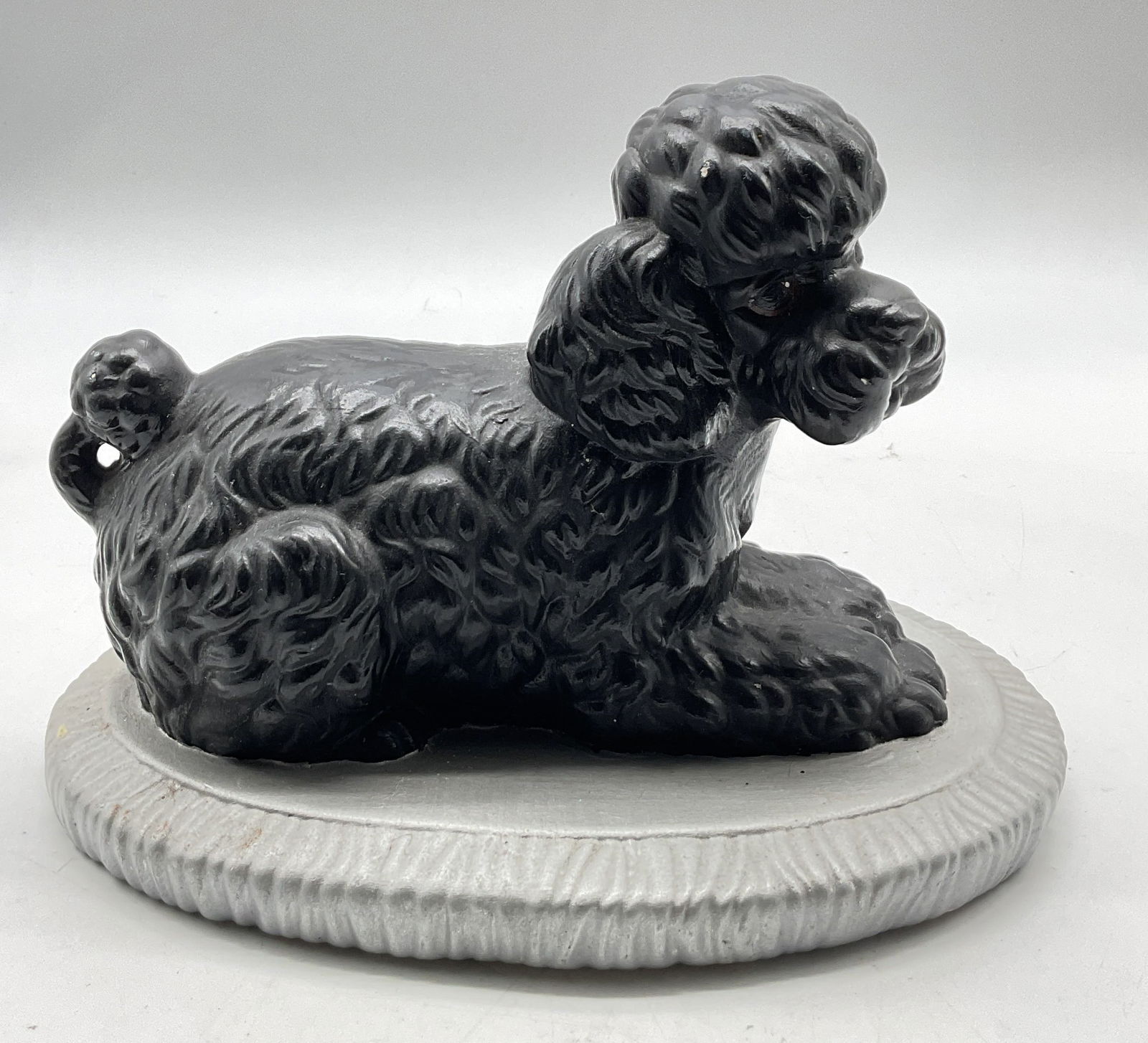 1981 Vintage Plaster Black Poodle Figure: Vintage plaster black poodle figure. Signed on underside, dated 1981. Black poodle in seated pose, hand painted. Rests on oval shaped silver toned base with ribbed surface. Detailed features and textu