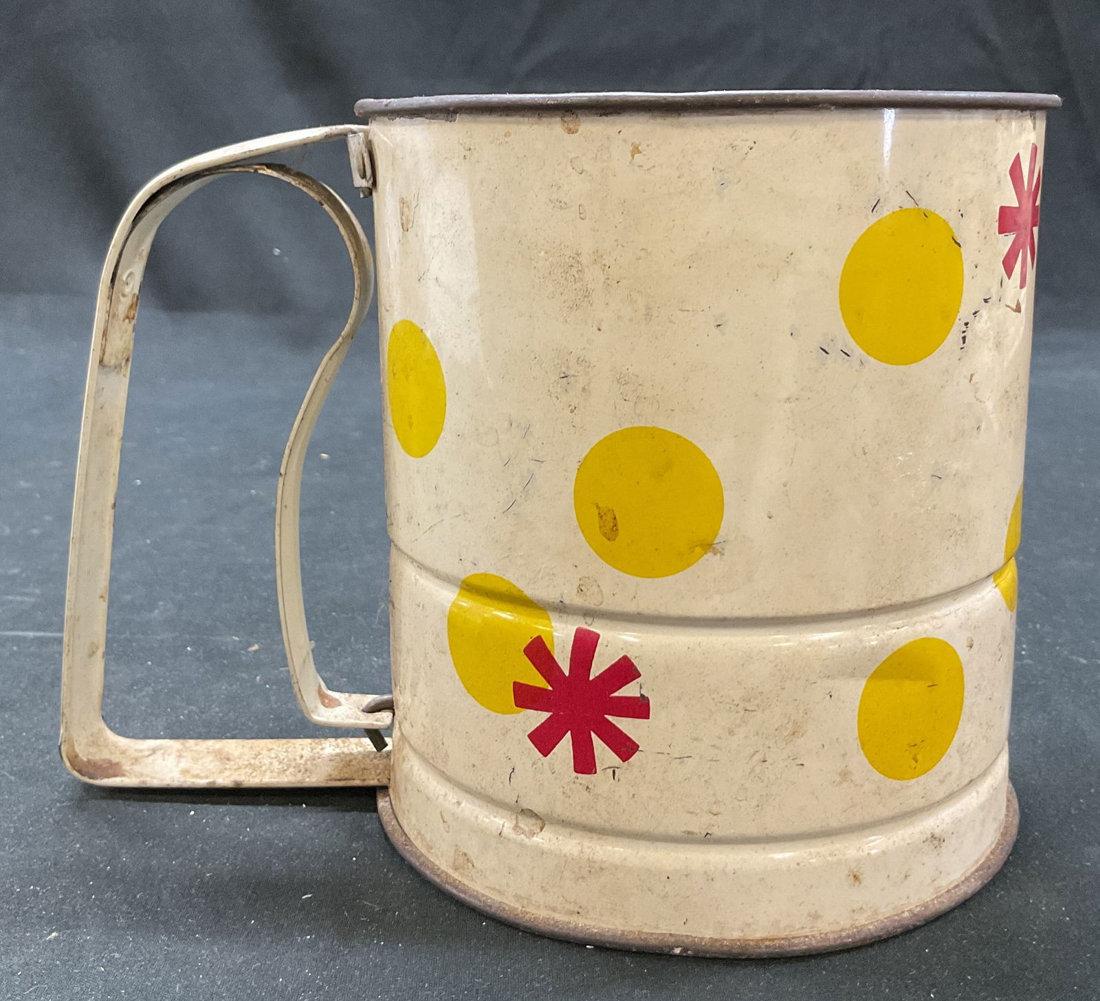 Androck Metal Flour Sifter USA: Androck metal four sifter. Made in USA. Side handle mechanism for operating the internal sifting agitator. White enameled with yellow polka dots and red starburst pattern. Measures ht approx 5.5