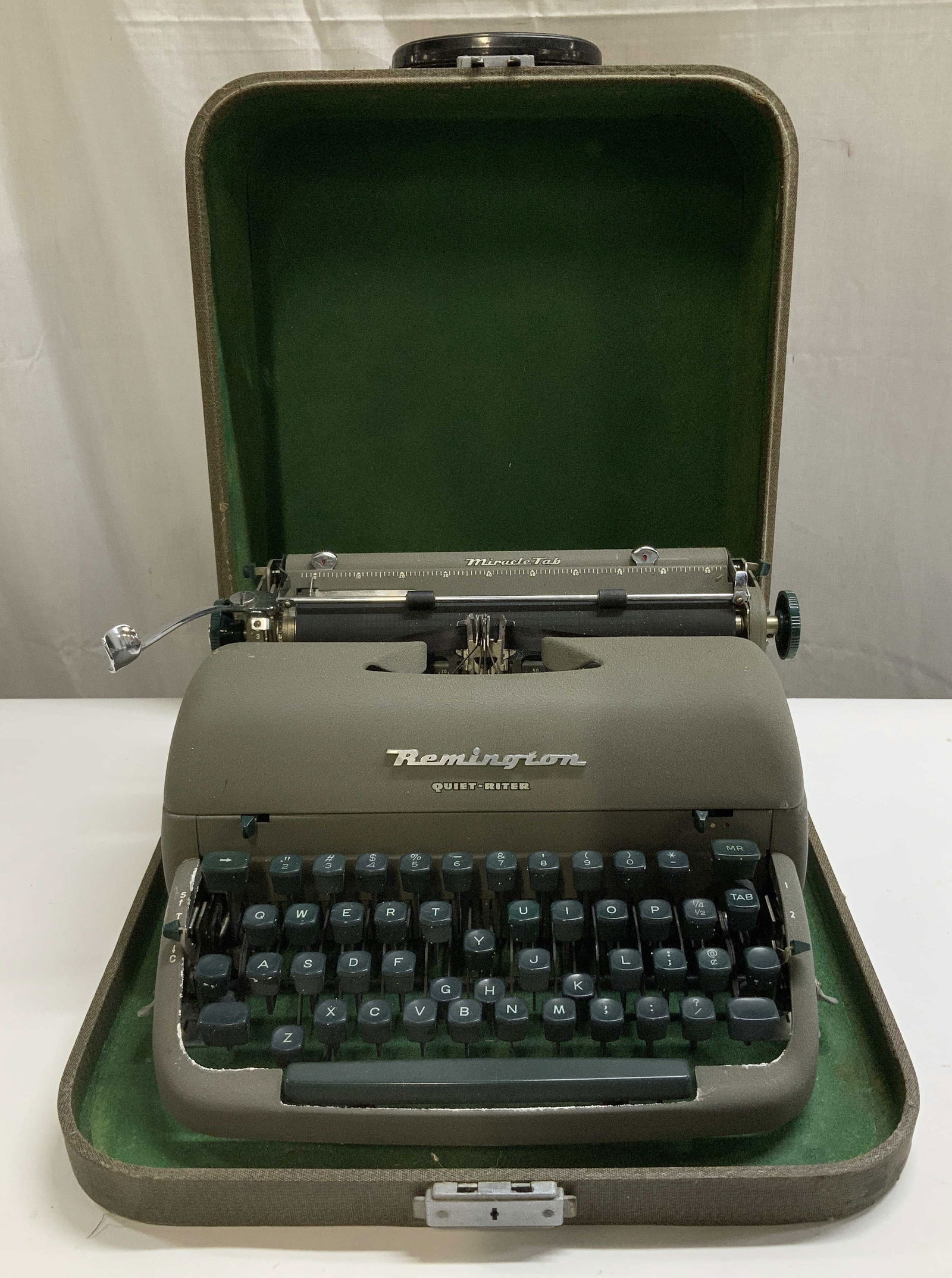 C.1950s Remington Quiet Riter Typewriter W Case: Vintage Remington Quiet-Riter portable typewriter. Comes in a carrying case & green interior lining. Typewriter is grey toned & has weight. Surface wear consistent to age, use & exposure. Measurements
