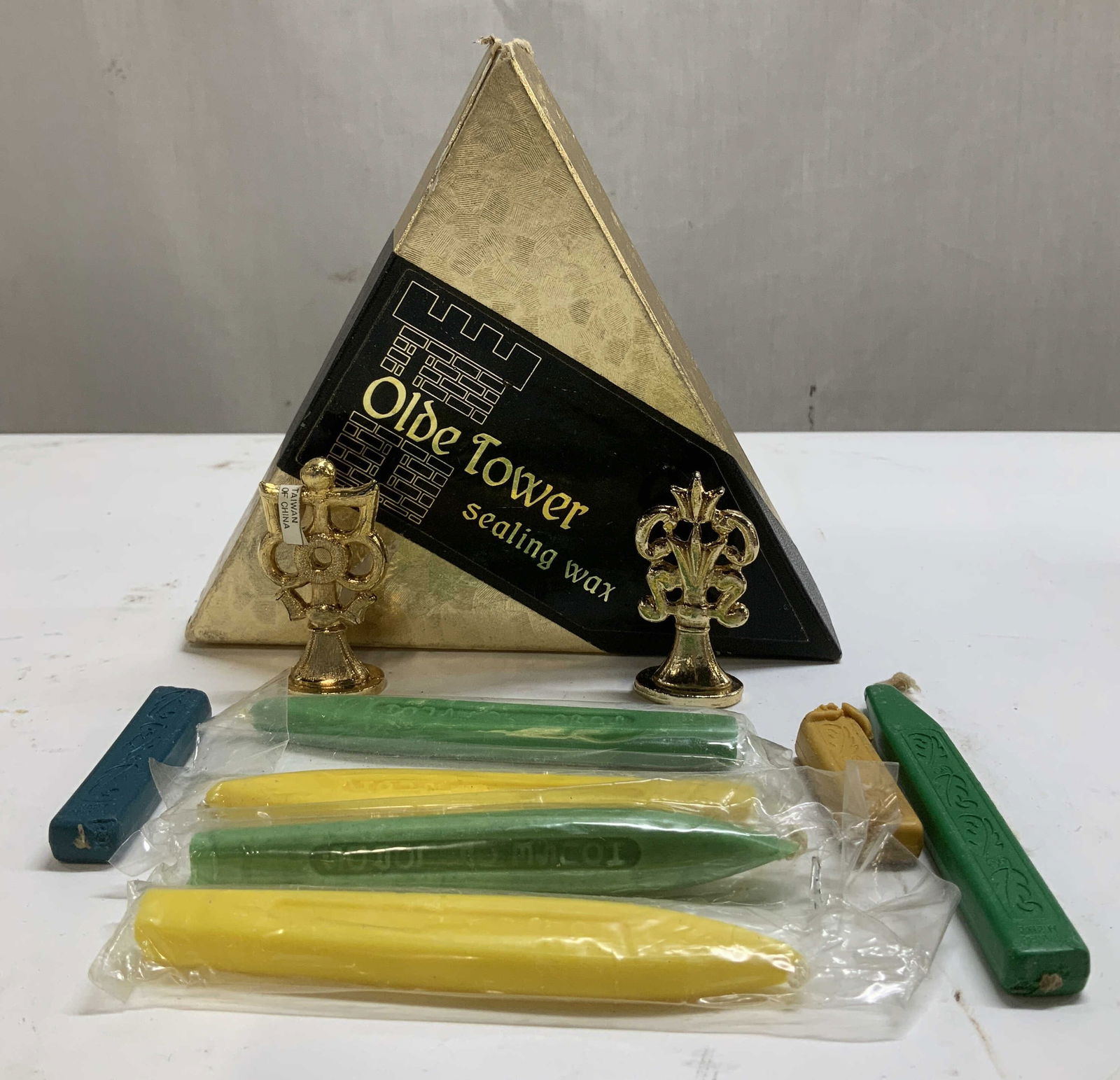 Lot 9 Olde Tower Sealing Waxes & Seal Stamps: Lot includes, 7 sealing waxes & 2 brass wax seal stamps. Comes in box that reads, Olde Tower sealing wax. Shades of yellow, green & blue. Property of opera singers estate from the renowned & opulent M