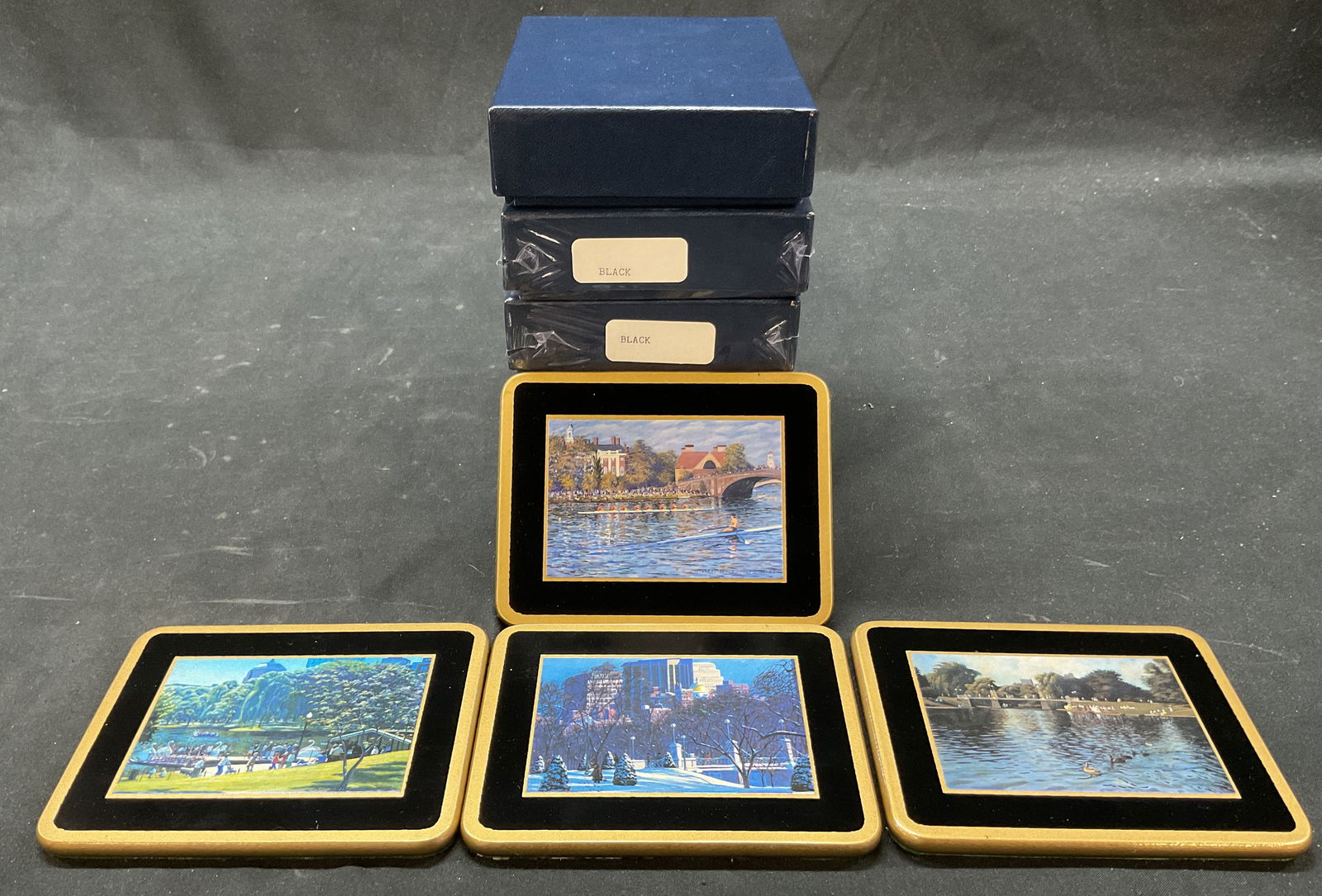 Lot 5 Ebbels Black Coasters England NIP: New in packaging. Five boxes. Unopened box has four black coasters. Reads Hand Made In England Ebbels. Wooden rectangular coasters with hand painted landscape imagery. Gilt accents. Measures approx 3.