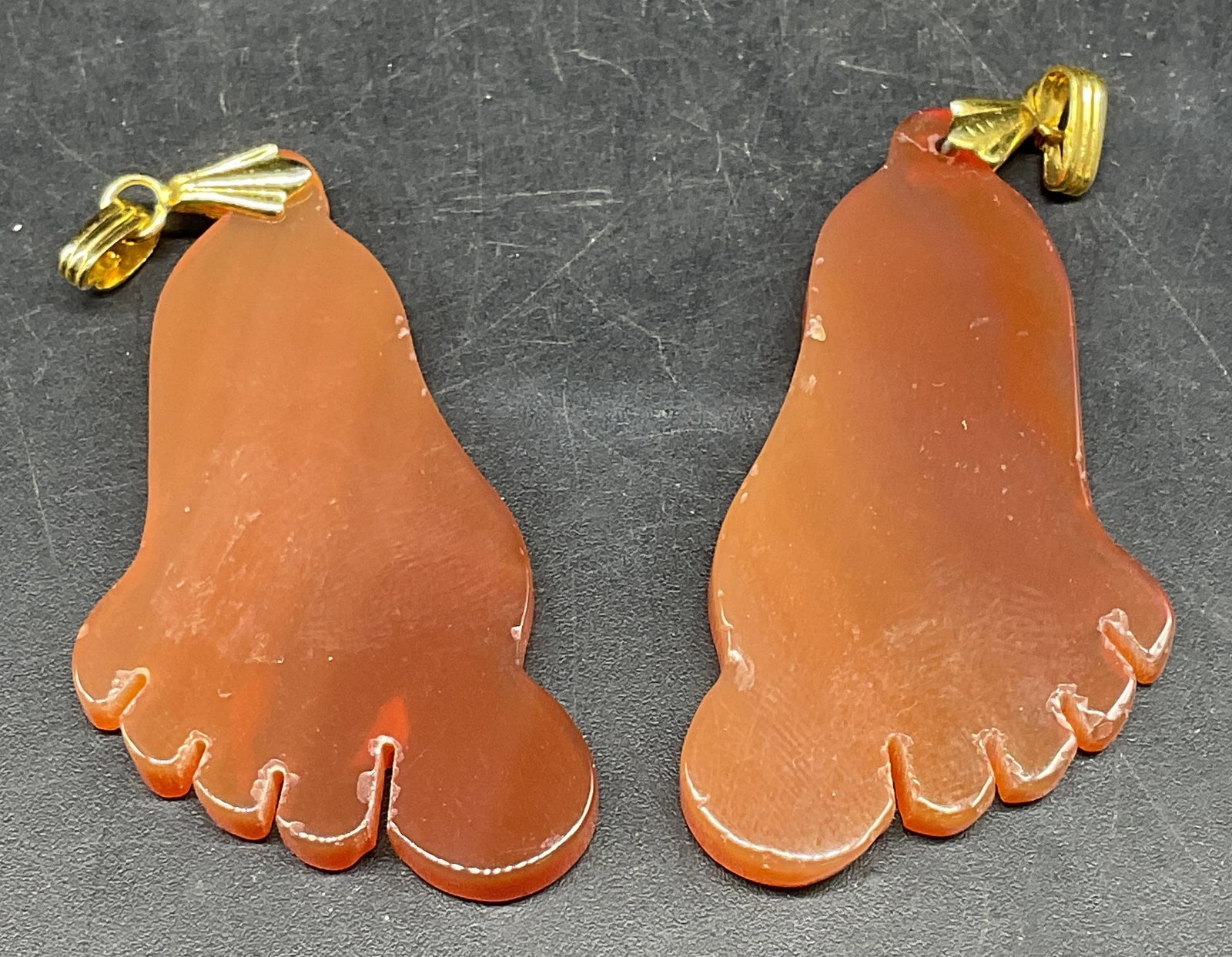 Pair Orange Semiprecious Foot Pendants: Pair of orange carved semiprecious stone foot motif pendants. Measures approx. 1.75 x 1 inches. Some scratching. Jewelry, estate jewelry, costume jewelry, cocktail jewelry, fashion jewelry, accessorie