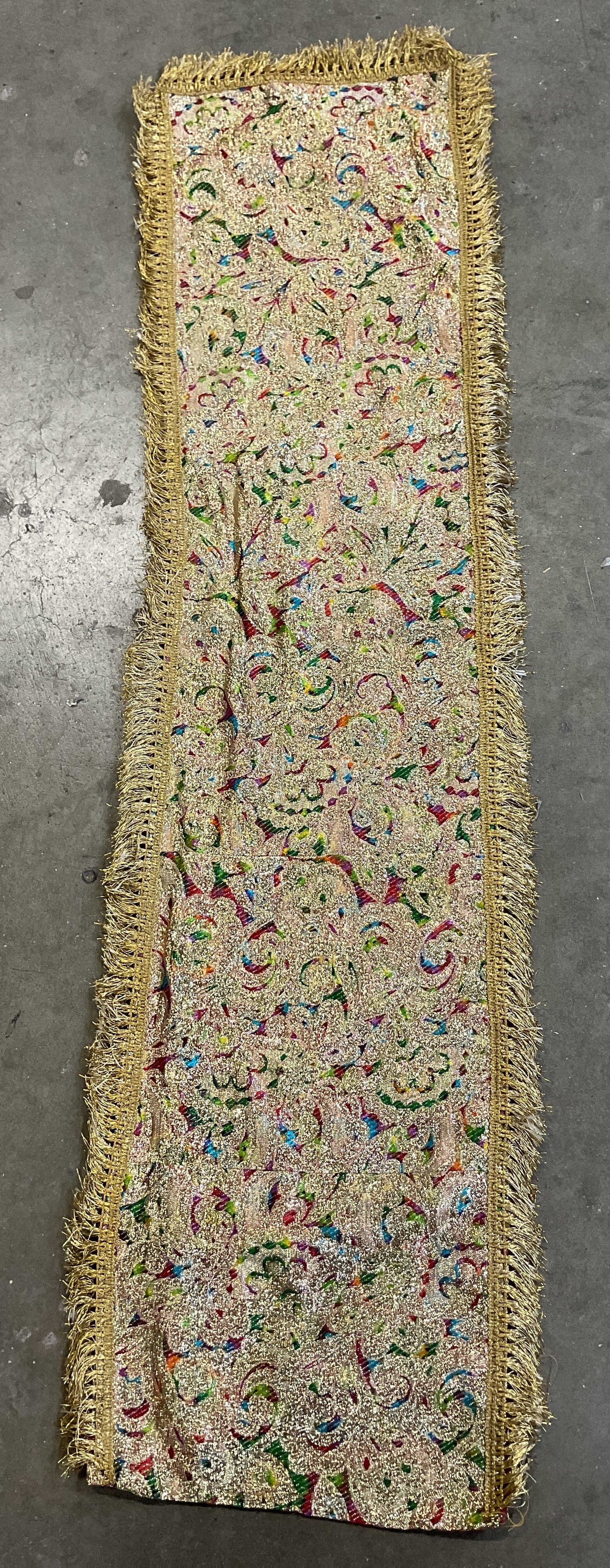 Vintage Embroidered Metallic Fringed Table Runner: Vintage embroidered metallic fringed table runner. Feels like silk. Metallic gold toned fringed trim. Embroidered floral motifs in blue, green, red, and more. Abstract patterns. Backside is red. Measu