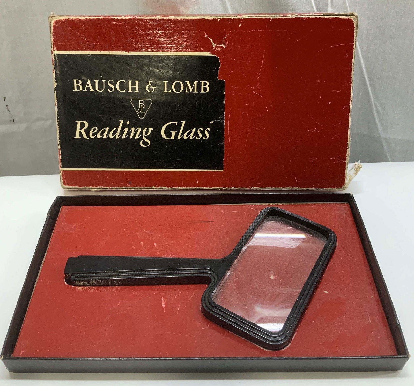 Vtg Bausch & Lomb Reading Glass W Org Box: Vintage Bausch & Lomb handheld reading glass. Features a rectangular lens. Comes in red & black original box. Lot is sold as is. It was manufactured by Bausch & Lomb, a company known for high-quality