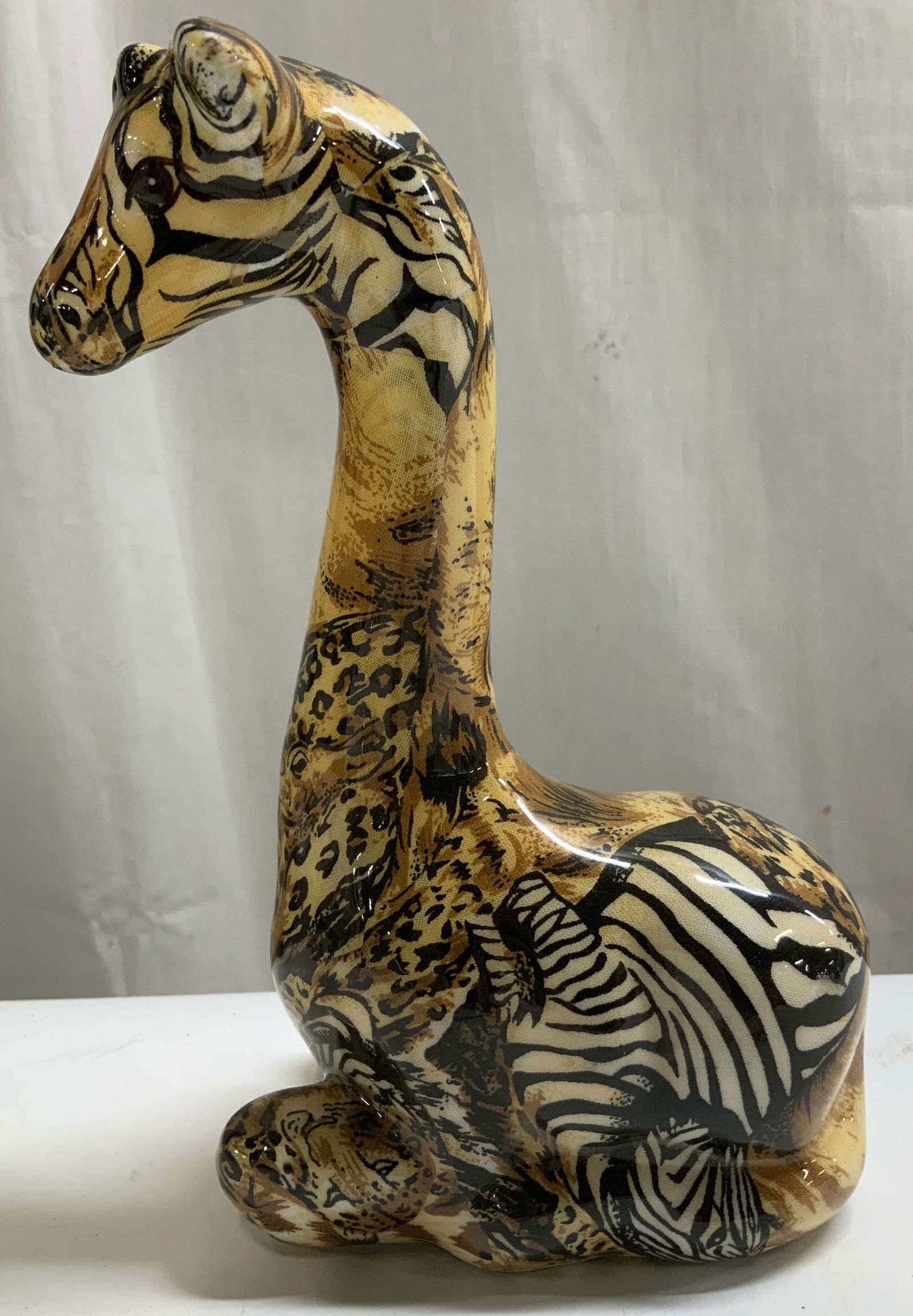Vtg Seated Ceramic Giraffe Figurine: Vintage ceramic figurine depicting a seated giraffe with a decoupage design with various animal prints. Glossy finish. Surface wear consistent to age, use & exposure. Measurements: length 5.2in x widt