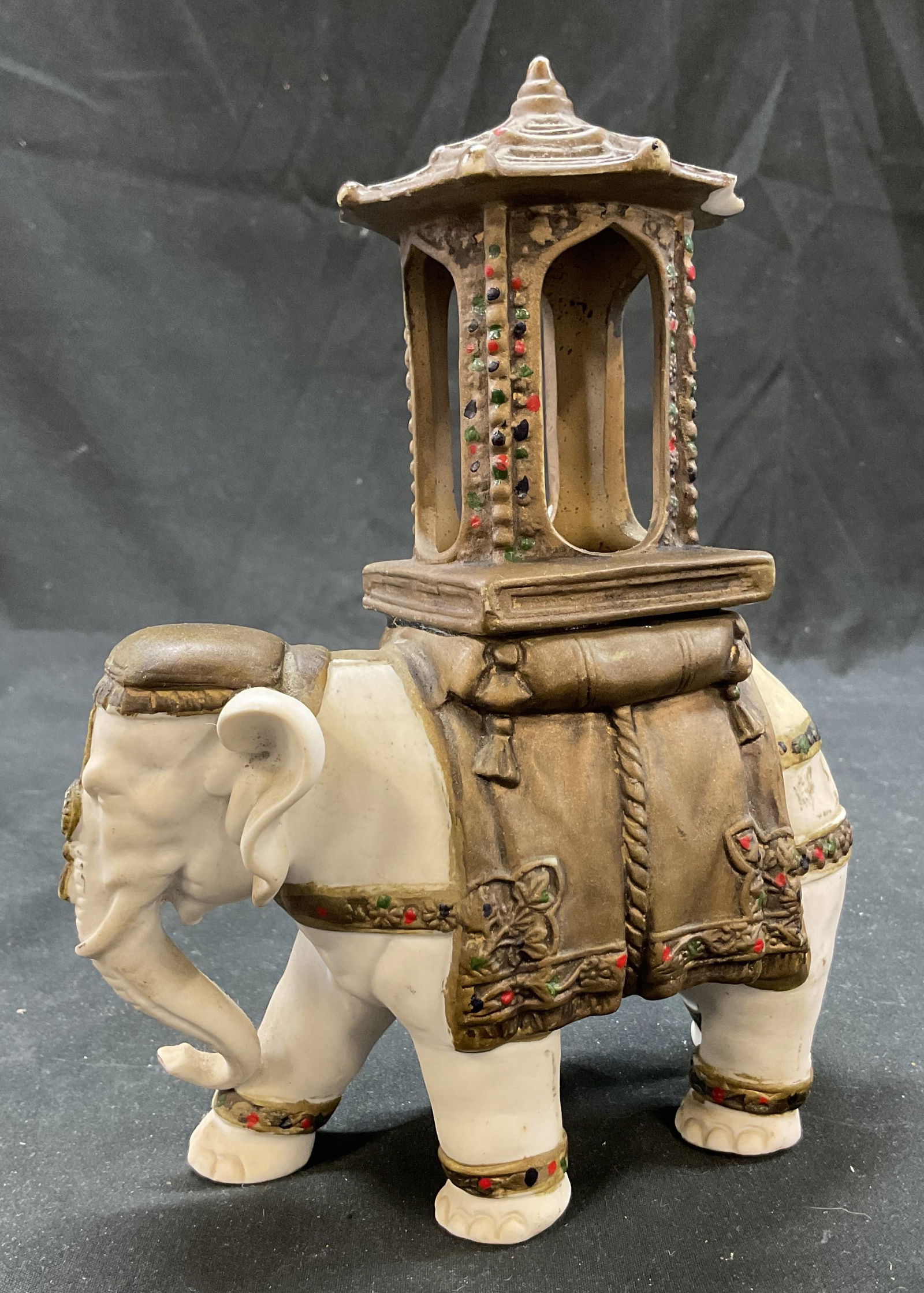 Vtg Chinese Porcelain Elephant Figural: Vintage Chinese bisque porcelain elephant figural. White elephant figure. Stylized structure on its back, tall with round flared top. Embossed leaf motifs. Ribbed surface. Gold toned. Hand