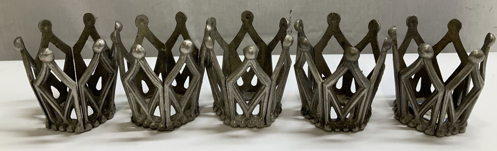 Set 5 Ambria Crown Metal Candle Holders USA: Lot includes, set 5 candle holders featuring a crown shape. Metal material. Signed & marked. Reads, AMBRIA. MADE IN U.S.A. Surface wear consistent to age, use & exposure. Measurements: length 3in x wi