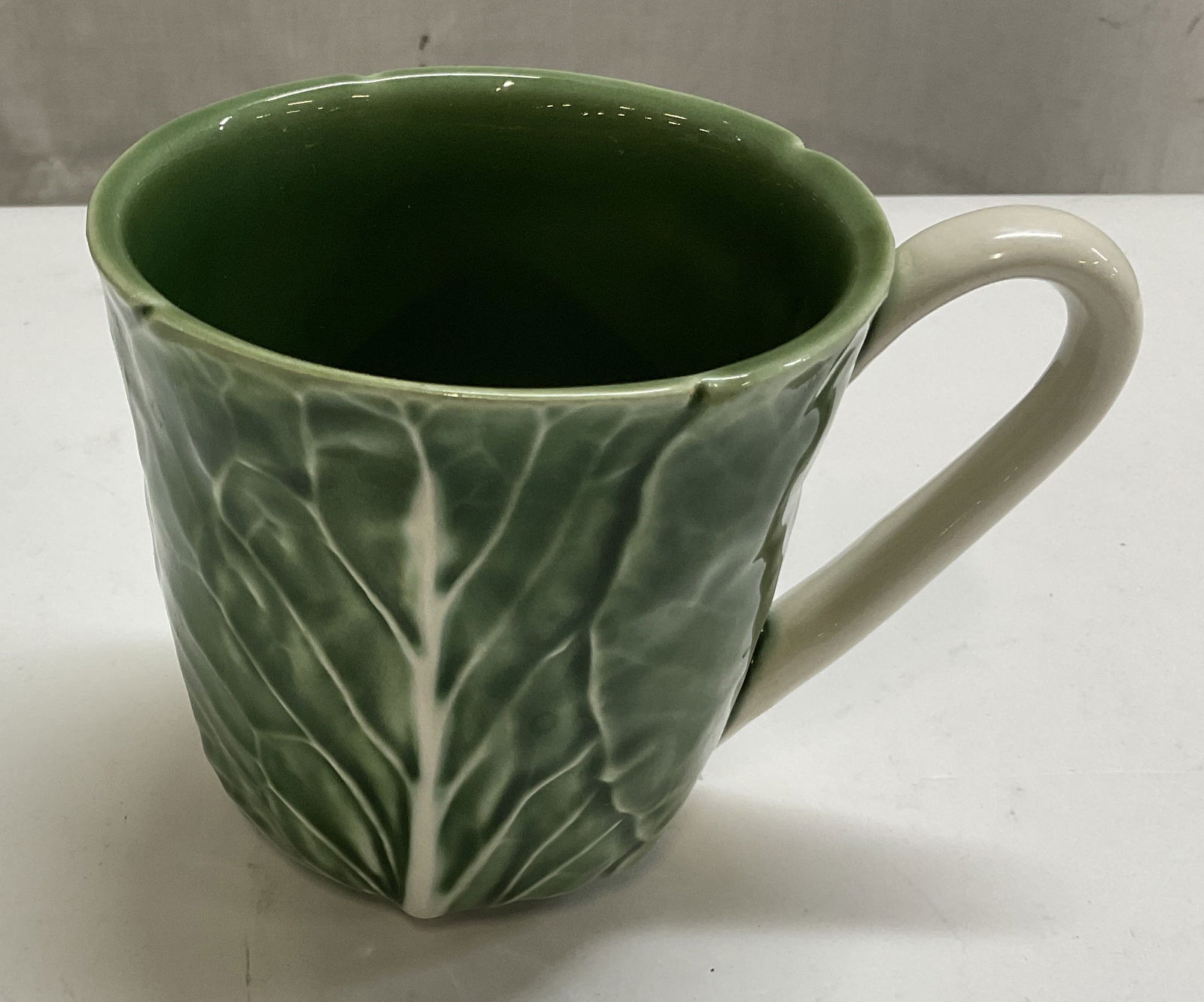 Bordallo Pinheiro Cabbage Mug Portugal: Bordallo Pinheiro Made in Portugal mug with a cabbage pattern. Slight chip on the rim of the mug. Measures approximately 3 x 4 inches. Bordallo Pinheiro, Portuguese art, cabbage pattern,