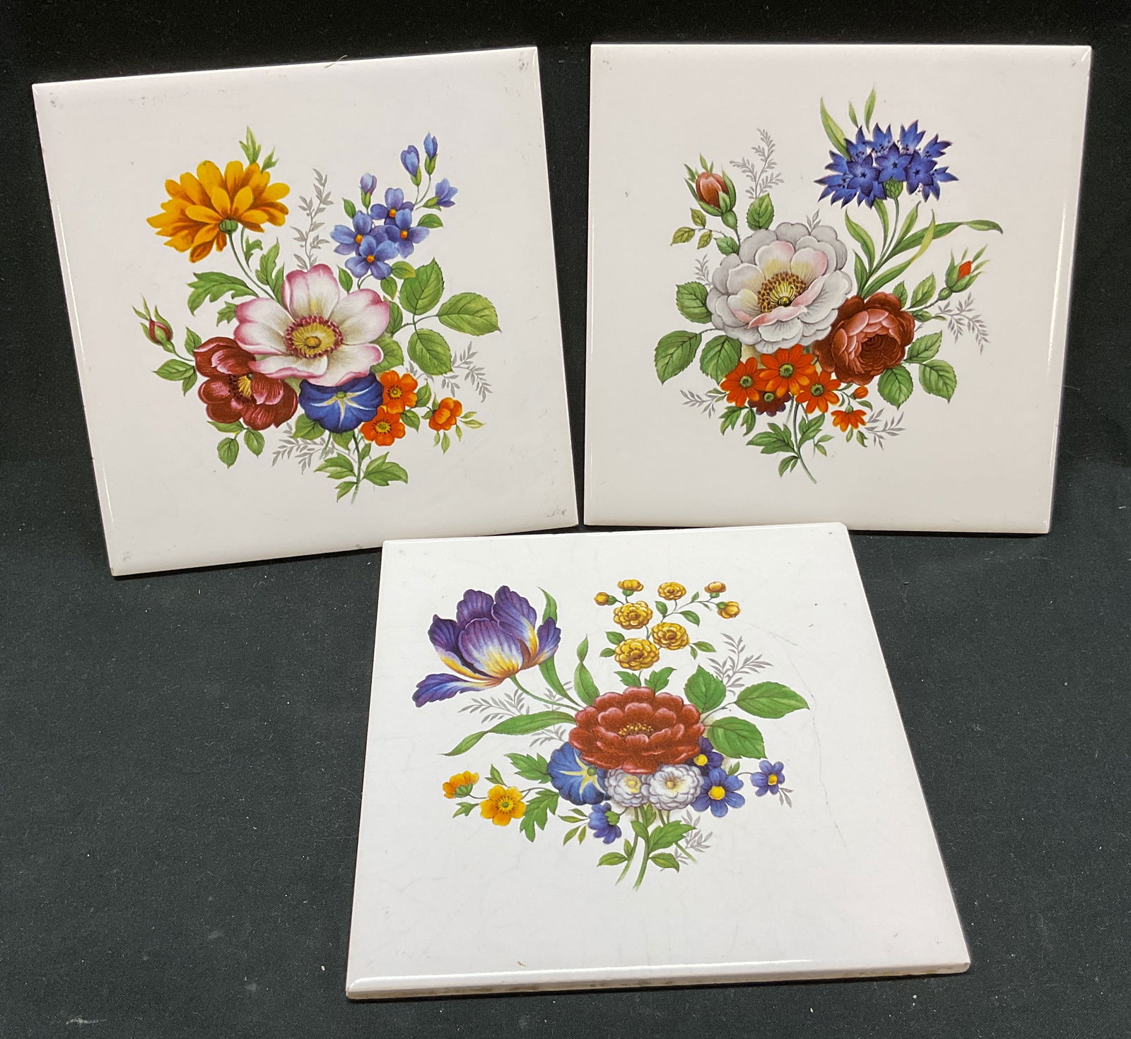 Set 3 Hyalyn Ceramic Floral Tiles: Lot of 3 Hyalyn ceramic floral tiles. Marked Hyalyn on underside. Square shaped. White background with floral motifs in varying colors. Measures approx 6 x 6 inches. Wear to surface. Hyalyn,