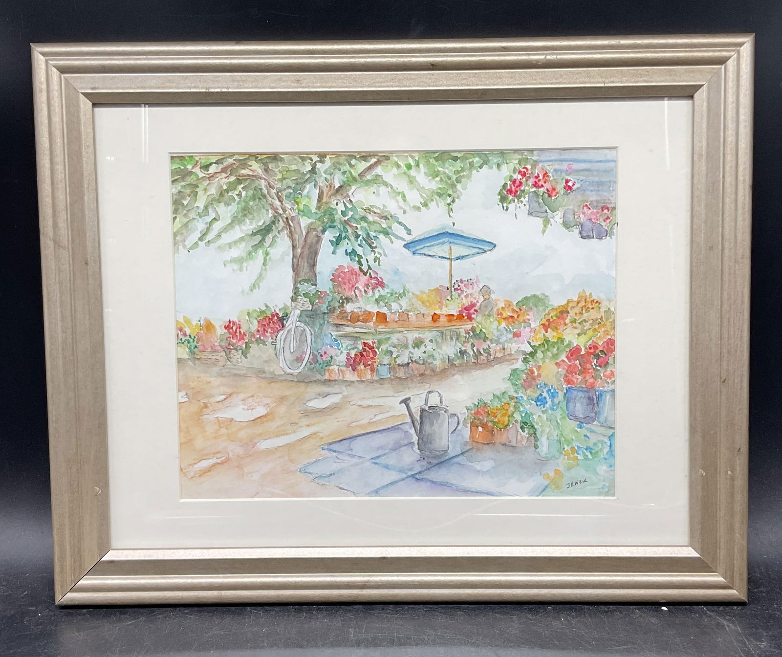 Signed Jeweir Garden Scene Watercolor Painting: Framed and matted watercolor painting. Signed lower right, Jeweir. Garden scene with flowers and figure. Silver tone wood frame. Not examined out of frame. Frame measures approx. 12 x 15 inches. Some