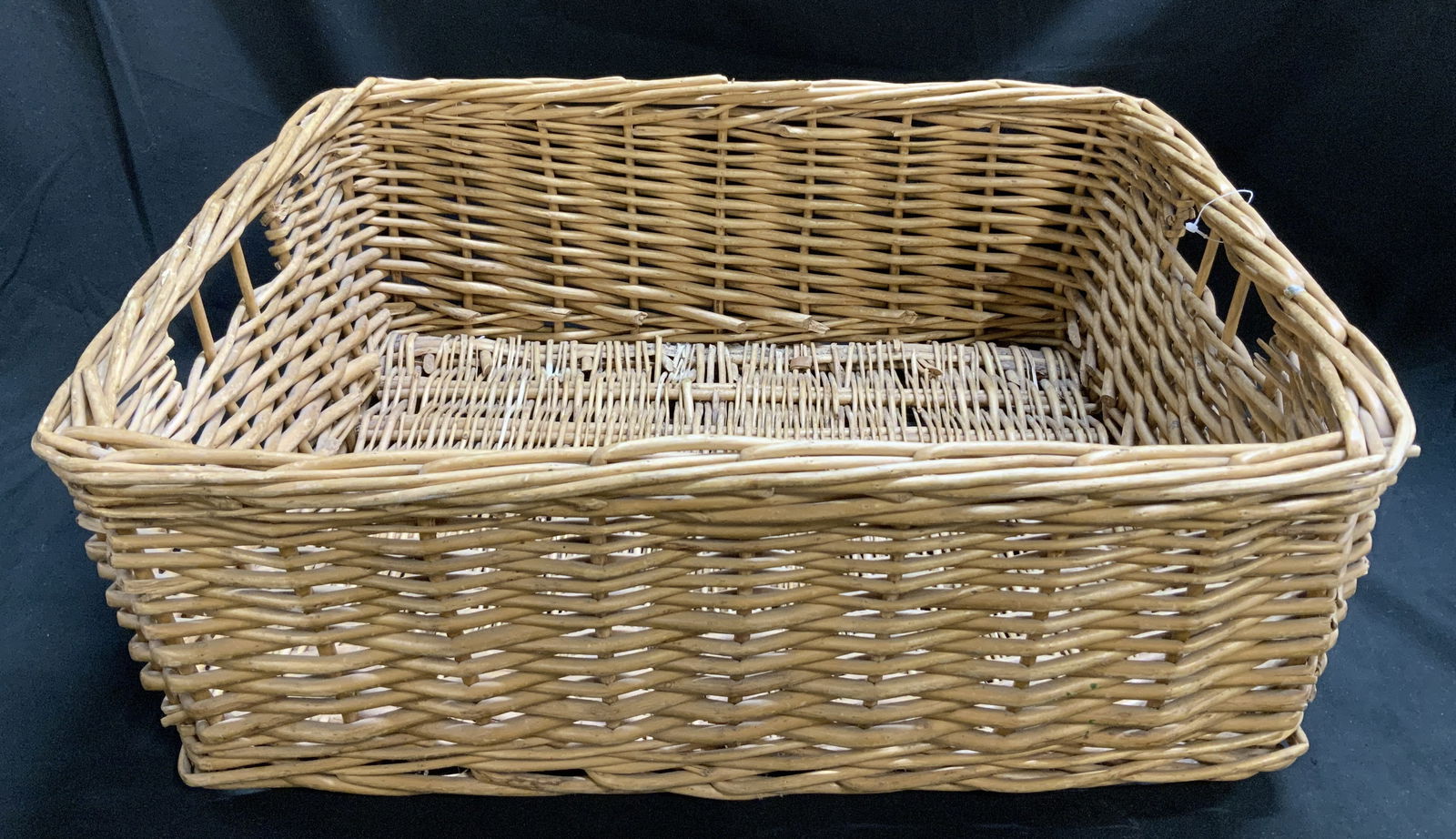 Rectangular Wicker Storage Basket: Wicker storage basket features a rectangular shape & distinctive side handles. Brown toned. No visible signature or markings. Surface wear consistent to age, use & exposure. Measurements: length