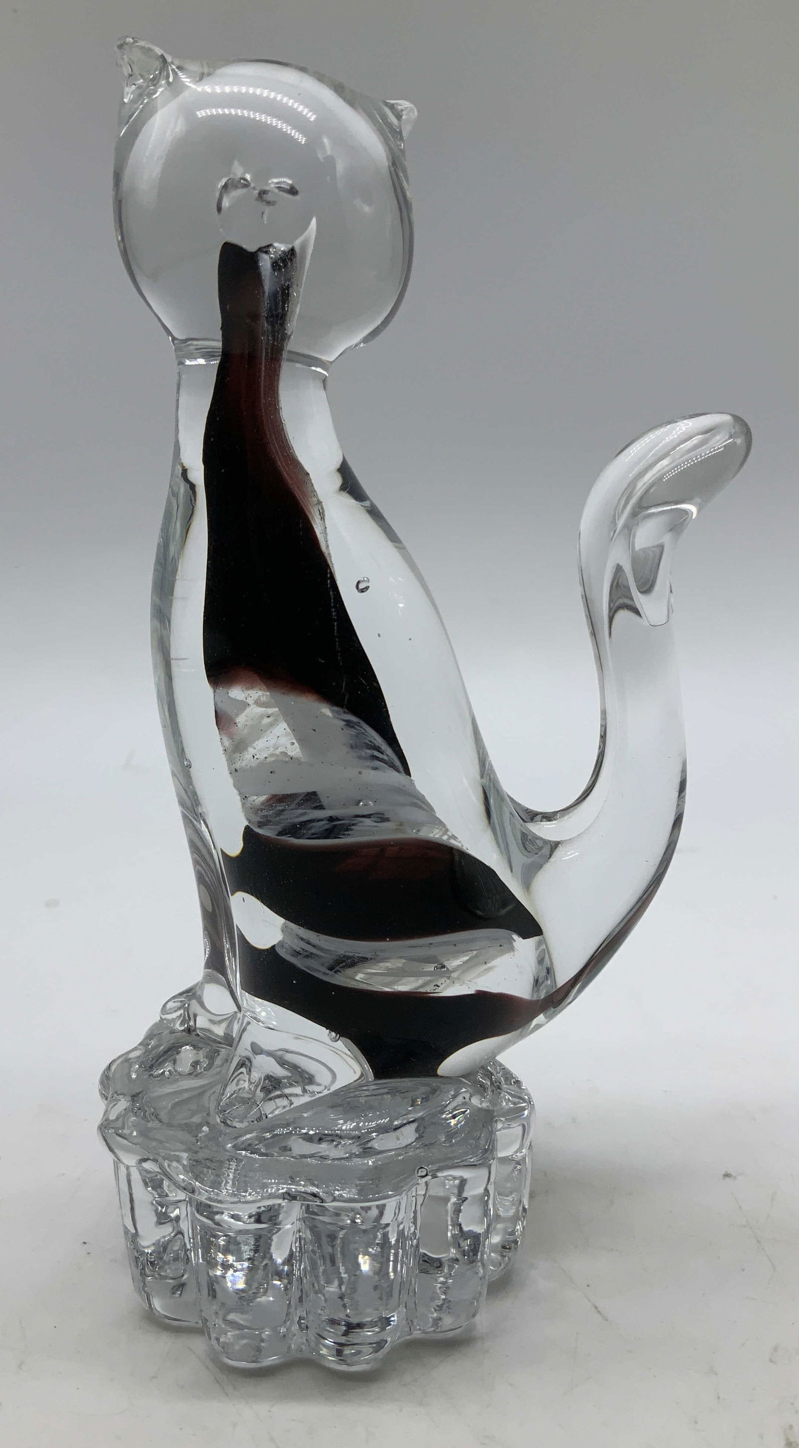 Vtg Hand Blown Art Glass Cat Figurine: Vintage handblown glass cat figurine, featuring a clear glass body with inner swirls of dark red & white. Cat is seated on a scalloped base. No visible signature or markings. Surface wear consistent t