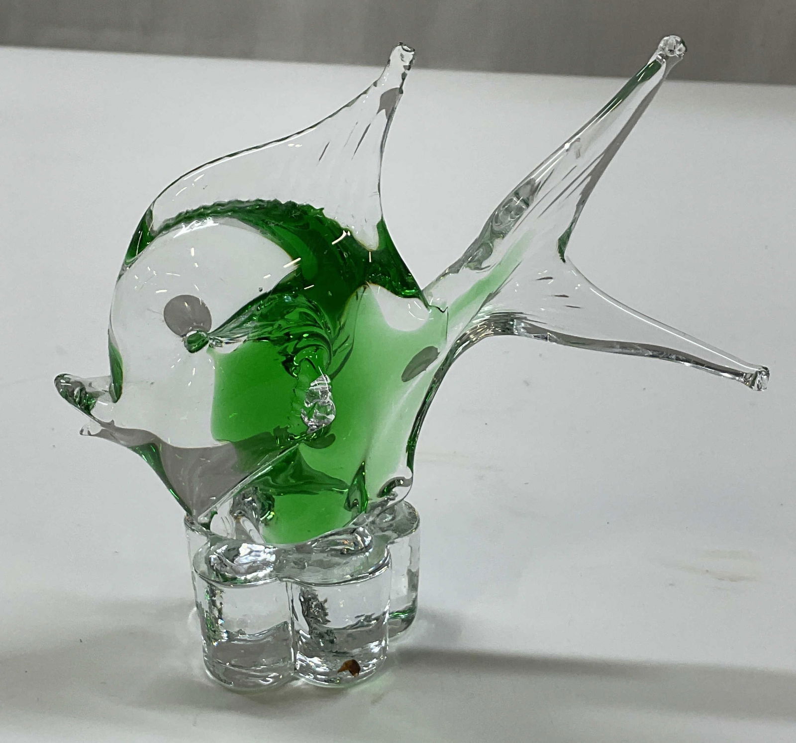 Hand Blown Art Glass Fish Figure: Hand blown art glass fish figure. Clear glass body with green swirled design. Fish sits on a ribbed scalloped base. No visible markings. Detailed features and textures. Measures approx 3.5 x 5.5 x 5 i