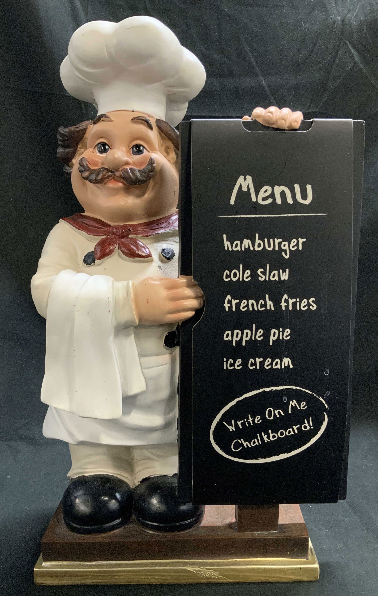 Mainstays Tabletop Chef Fig W Chalkboard: Mainstays tabletop chef figurine holding a chalkboard. Shades of white, brown, red & black. Appears to be resin material. Signed & marked on underside. Reads, MAIN STAYS. Surface wear consistent