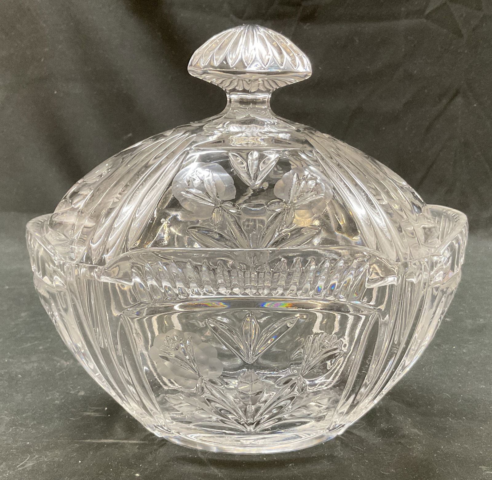 Vintage Cut Crystal Lidded Candy Bowl: Vintage cut crystal lidded candy bowl. Oval shaped with scalloped edges. Cut designs featuring floral motifs, criss cross patterns, ribbed pattern, and fan pattern. Decorative round ribbed finial on l