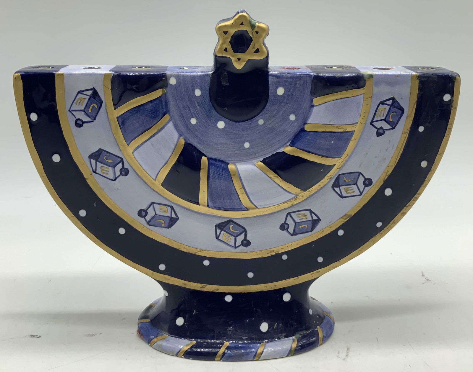Cardinal Hand Painted Ceramic Hanukkah Menorah: Ceramic Hanukkah menorah features hand painted details. Shades of blue, white & gilt accents. Star of David at top. 9 arms. Signed & marked on underside. Reads, HAND PAINTED CERAMIC. CHANUKAH LIGHTS.