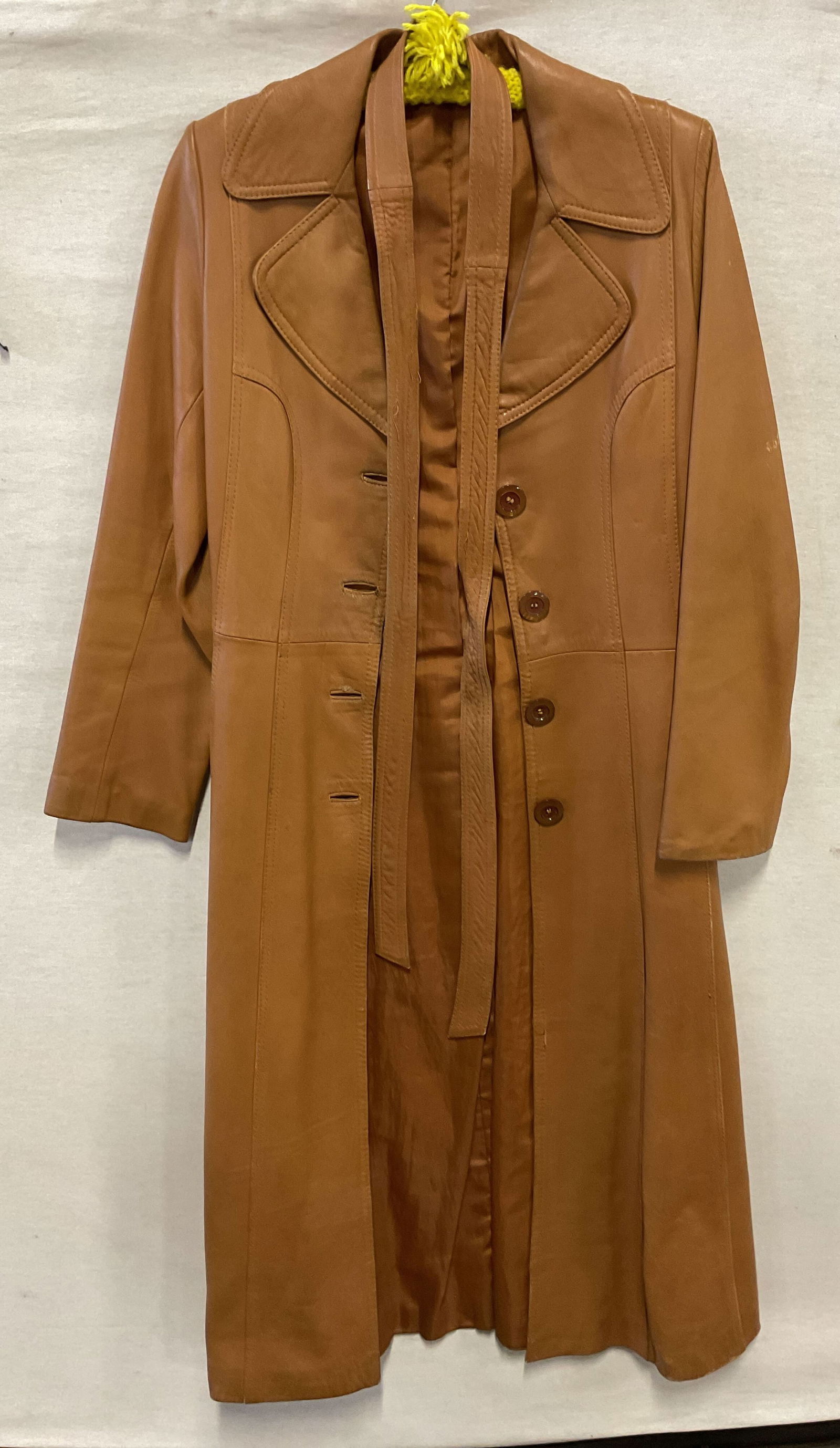Vtg Brown Leather Buttoned Trench Coat W Belt: Vintage brown leather buttoned trench coat. Includes belt. No visible markings or tags. Leather material. Collared coat. Front pockets. Decorative buttons going top to bottom. Measures approx 20