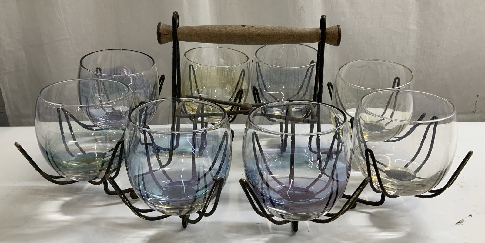 Lot 8 Vtg Colored Glasses & Wire Caddy: Lot includes, 8 colored glasses featuring a roly-poly shape & wire caddy with a wooden handle. No visible signature or markings. Sold as is. Surface wear consistent to age, use & exposure. Measurement