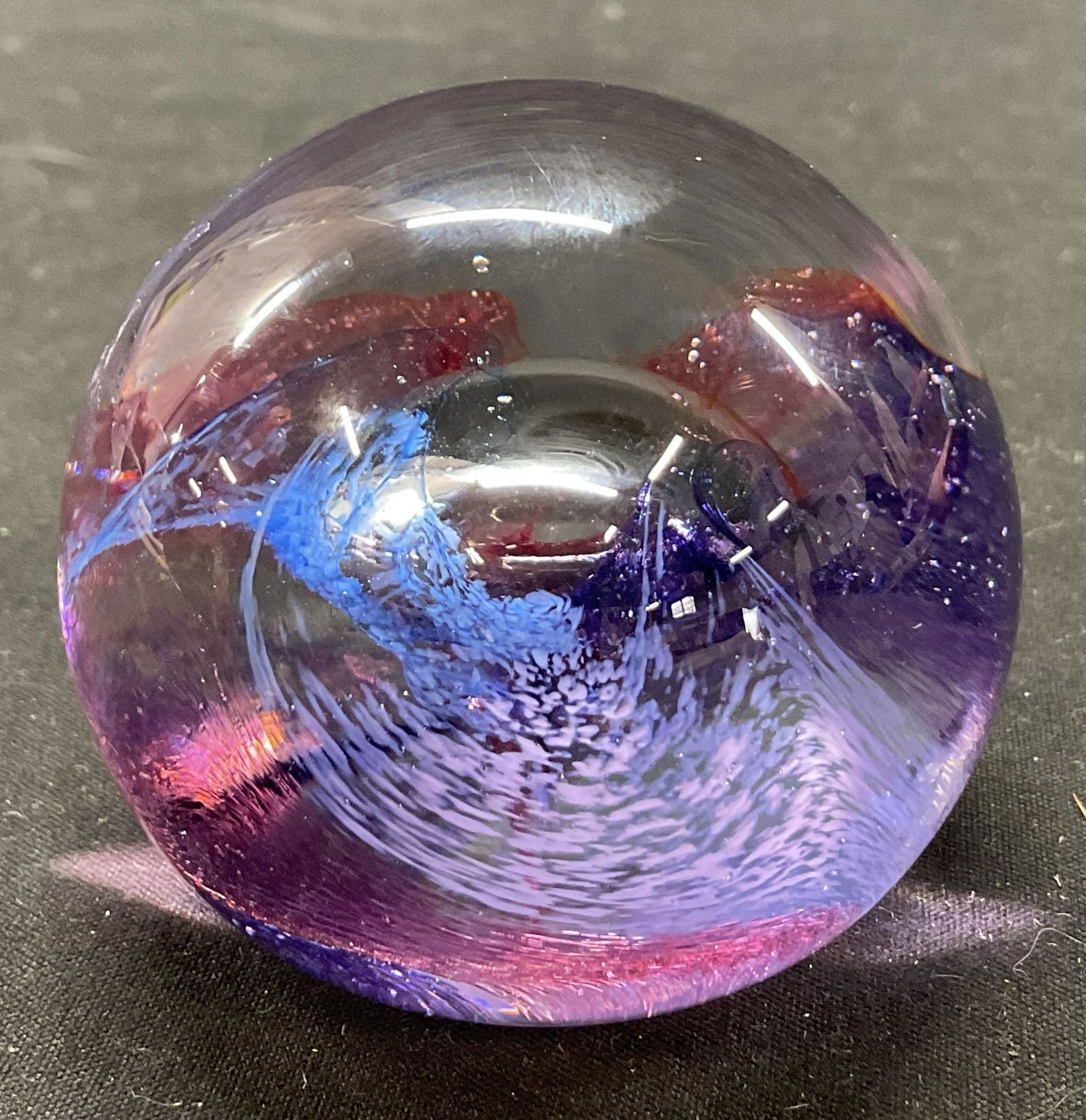 Caithness Art Glass Paperweight Scotland: Caithness hand blown art glass paperweight. Marked on underside, reads Caithness Mooncrystal Scotland. Dome shaped. Blue and purple swirl design. Bubble design. Measures ht approx 2 inches diam approx