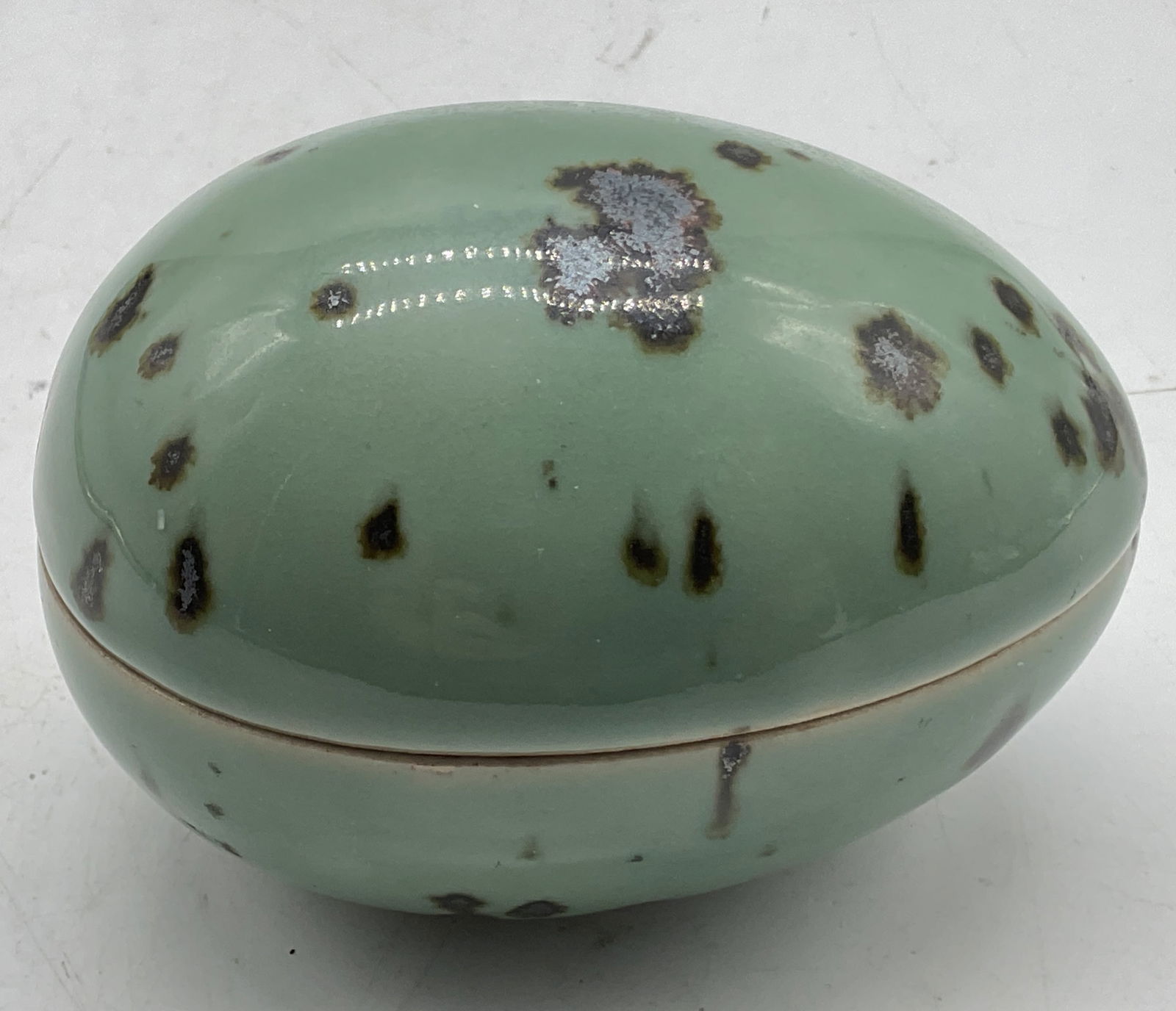 Dansk Ceramic Egg Shaped Trinket Box Japan: Dansk ceramic egg shaped lidded trinket box. Marked on underside, reads Dansk International Designs LTD Japan. Egg shaped box. Light green with brown silver toned speckled pattern. Glossy finish. Meas