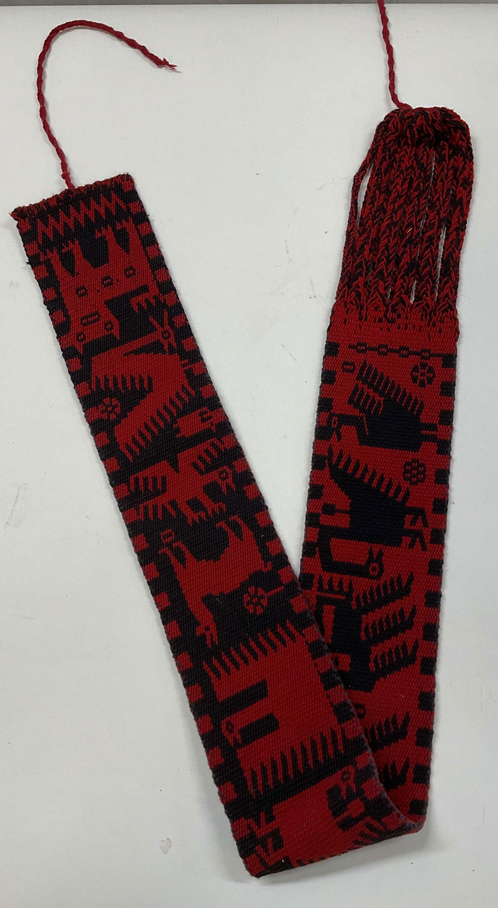 Handcrafted Woven Animal Wall Tapestry: Handcrafted woven animal wall tapestry. Rectangular shape with cut out fabric design. Black and red. Animal figure motifs. Geometric patterns. Strings at either end. Measures approx 4 x 40