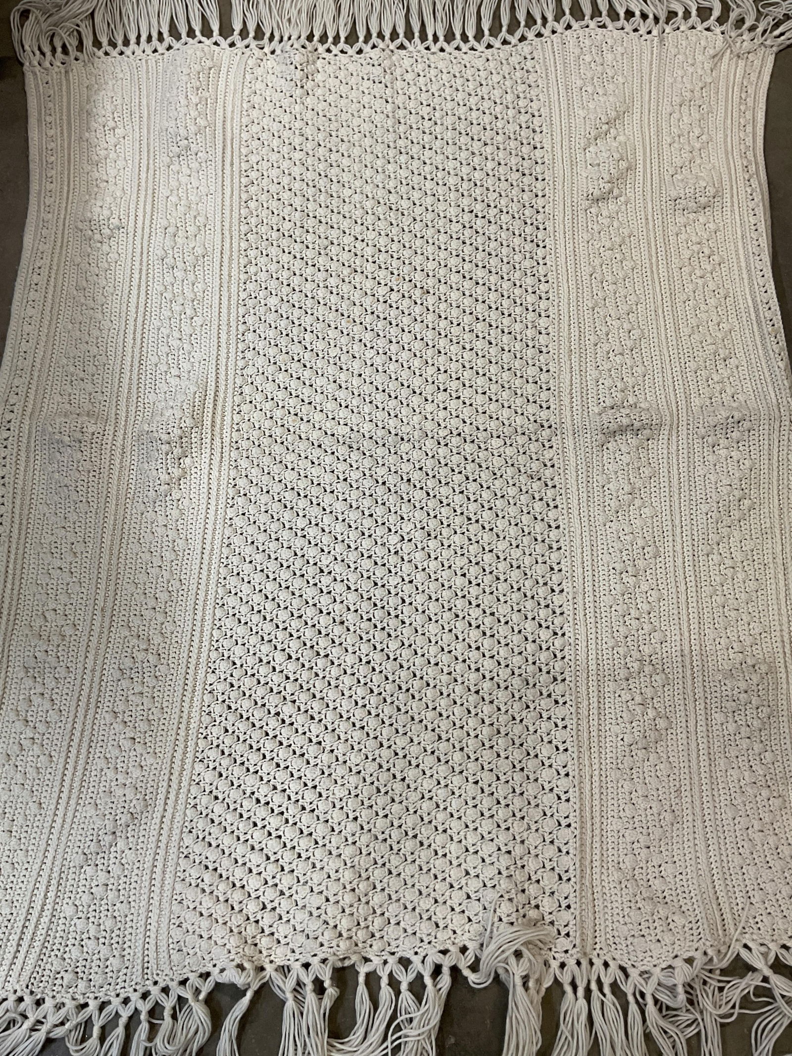 Vintage Cream Colored Knit Fringed Throw Blanket: Vintage cream colored knit fringed throw blanket. Feels like wool. Cream colored fringed trim. Geometric pattern design. Measures approx 47 x 56 inches. Surface wear consistent with exposure.