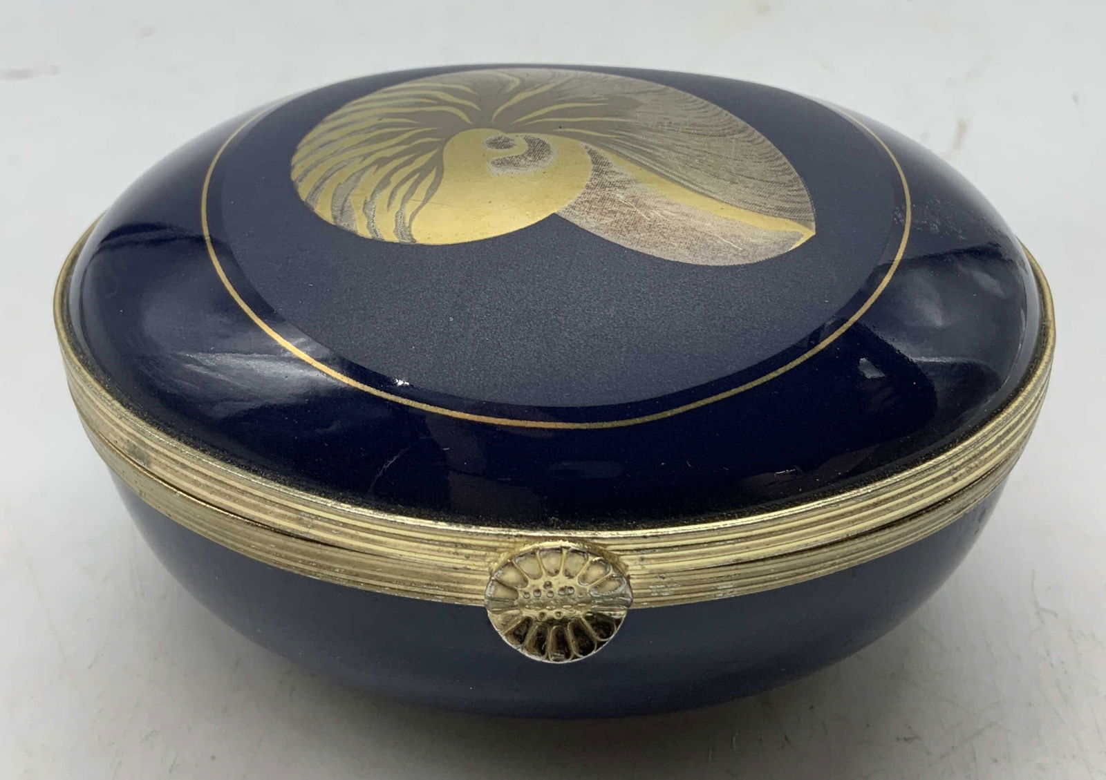 Vtg Nautilus Seashell Trinket Box OTAGIRI JAPAN: Vintage Nautilus trinket box features a porcelain body with a shell design on lid. Blue toned. Gilt accents. Signed & marked on underside. Reads, Nautilus Otagiri Japan. Surface wear consistent
