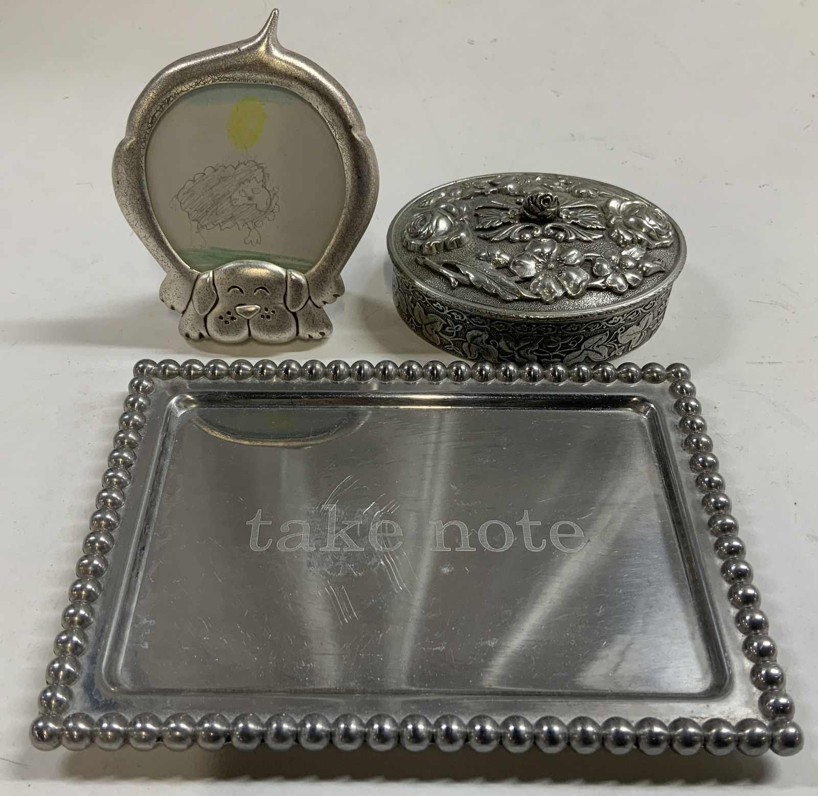 Lot 3 Silver toned & Pewter 1991-2013 Home Decor: Lot includes, 1 silver toned dig picture frame, 1 silver toned Take Note tray & 1991 Heritage Pewter ornate trinket box. Assorted sizes. Surface wear consistent to age, use & exposure. Signed &