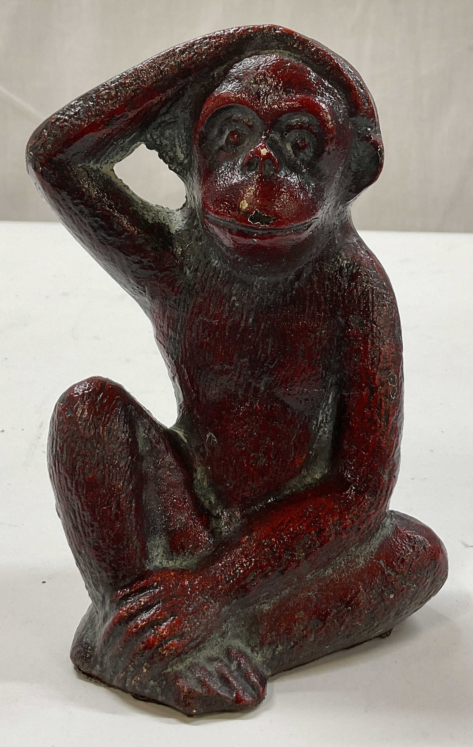 Vintage Cast Iron Monkey Figure: Vintage cast iron monkey figure. Seated position with one hand on its head. Reddish tone. Detailed features and textures. Heavy base. Measures approx 3 x 5 x 6 inches. Some chipping to surface. Monkey