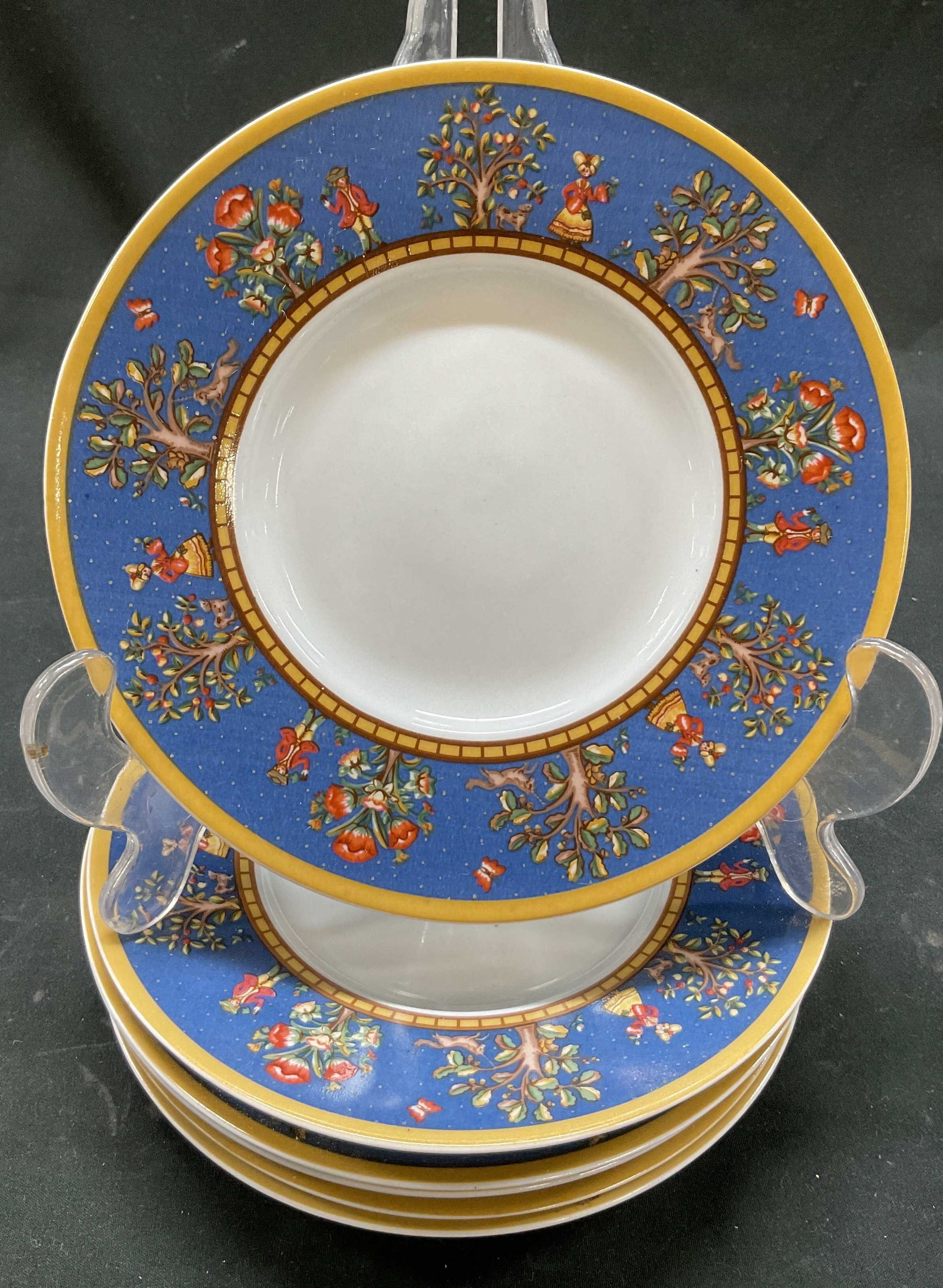 Set 6 1995 Domestications Colonial Porc Plates: Domestications Colonial porcelain plates. Marked on underside, reads Made Exclusively For Domestications Copyright 1995. Round plates. Gilt rim. Tree, floral, animal, and figure motifs on border in va