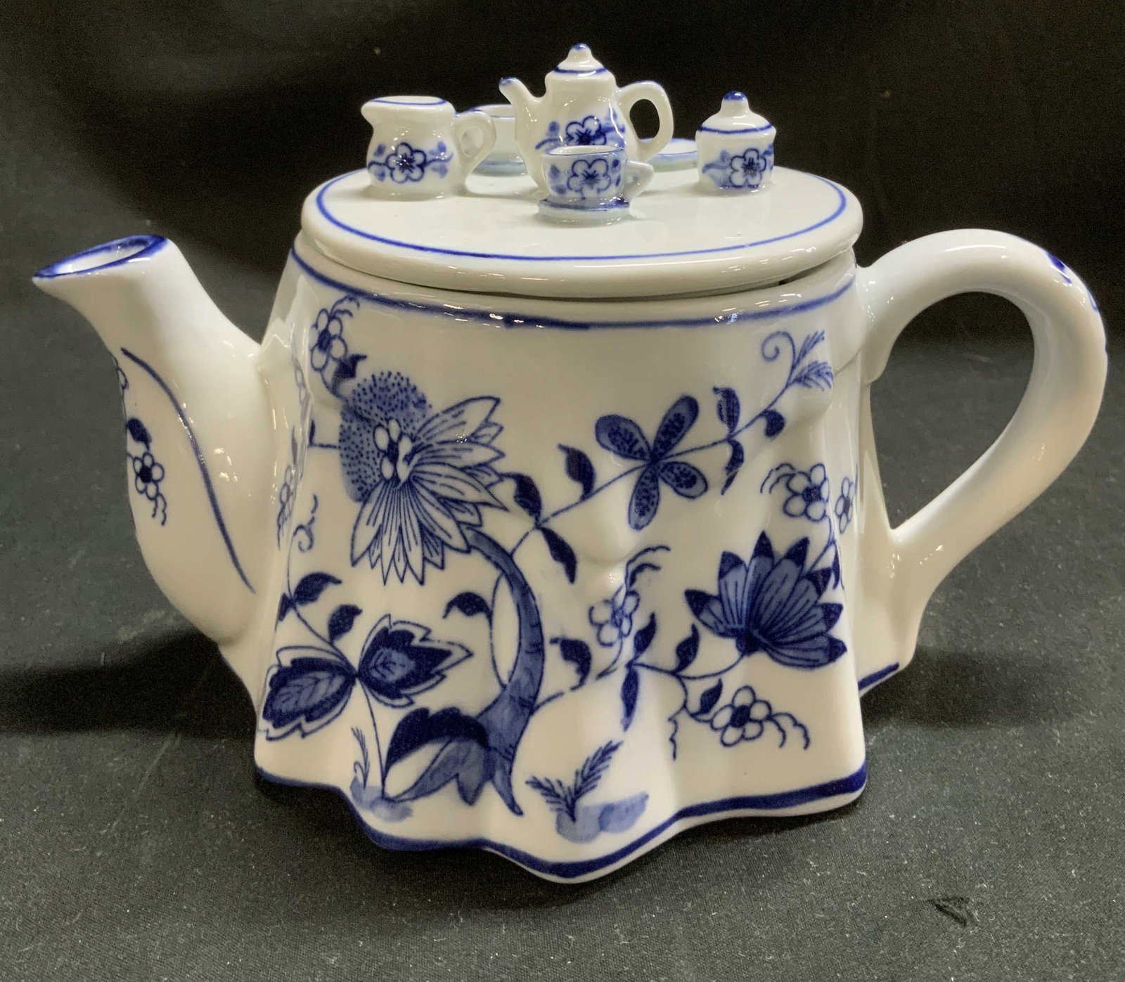 1992 Vienna Woods Mann Porcelain Teapot: 1992 porcelain teapot with a blue & white floral pattern on body. Miniature tea set on lid. Signed & marked on underside. Reads, VIENNA WOODS. FINE CHINA. 1992. Surface wear consistent to age, use & e