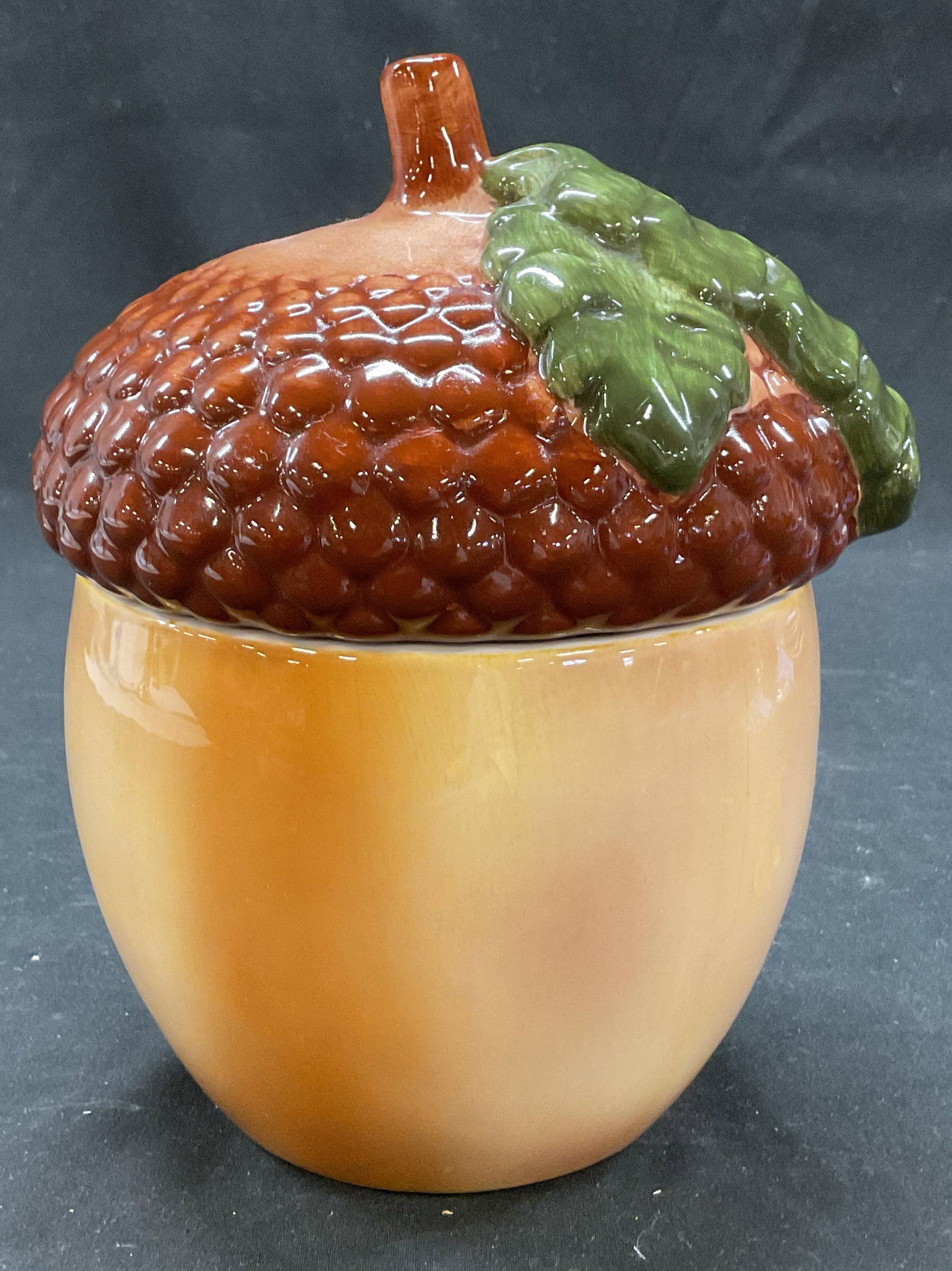 Teleflora Ceramic Acorn Cookie Jar Philippines: Teleflora ceramic acorn cookie jar. Marked on underside, reads A Teleflora Gift Teleflora Made In Philippines. Round brown and white body. Lid has raised circular pattern to mimic an acorns texture. B