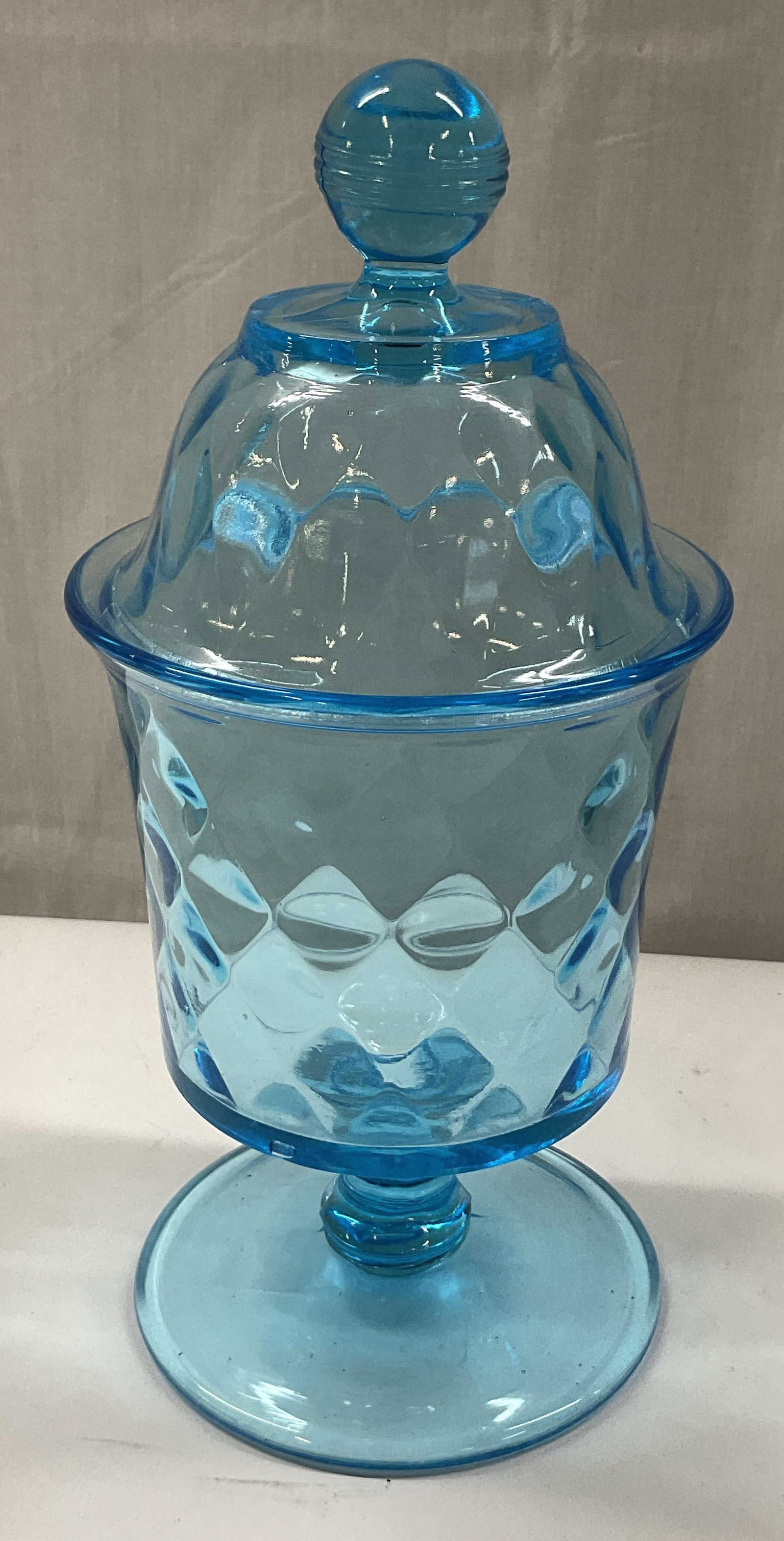 Vtg Blue Glass Lidded Pedestal Candy Dish: Vintage blue glass lidded pedestal candy dish. Round pedestal base. Round body with raised diamond like pattern. Repeating pattern on lid with decorative round sphere finial. Measures ht approx 9.5 in