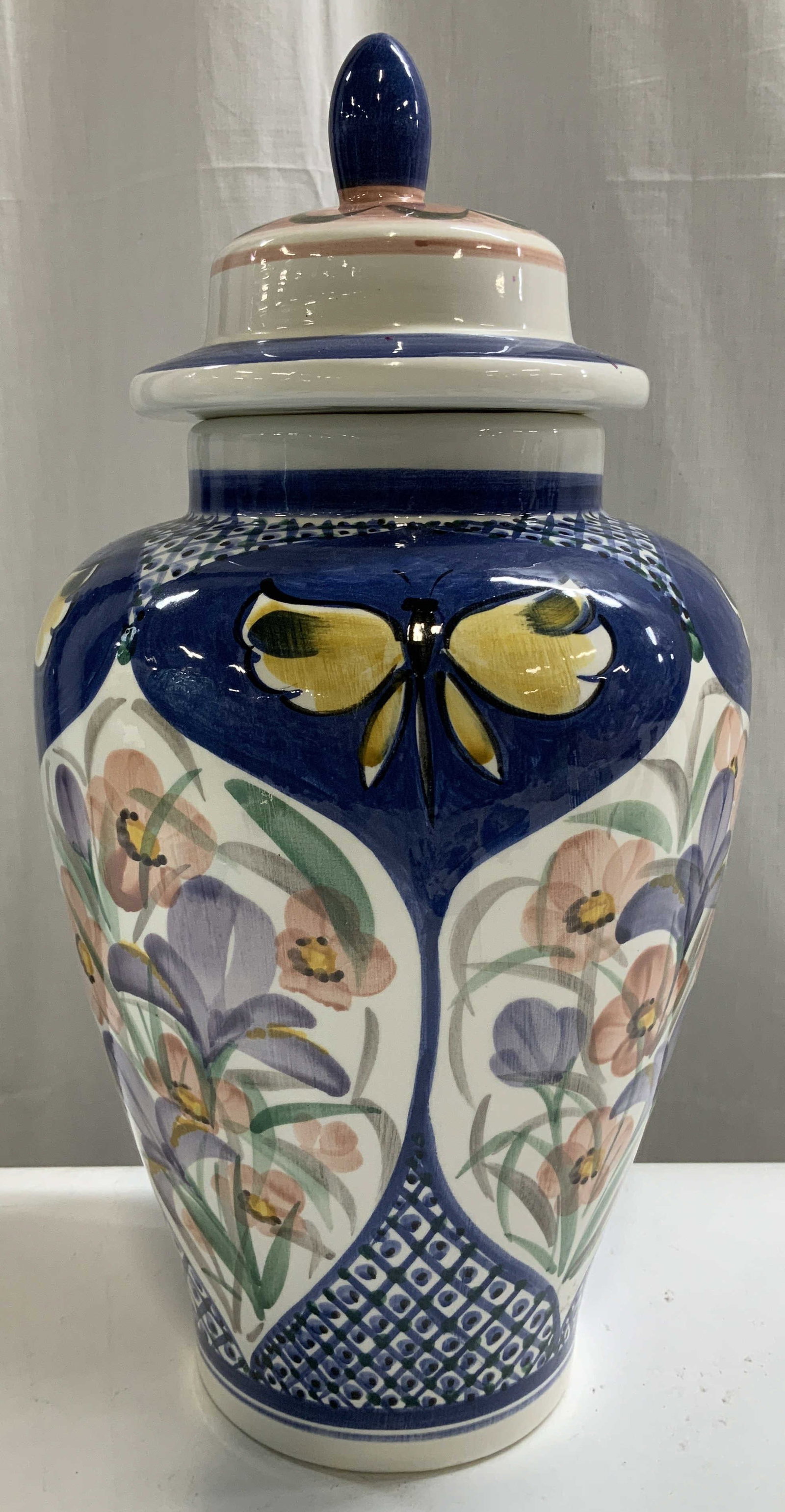 Hand Painted Ursula Ceramic Lidded Vessel: Lidded vessel features hand painted vibrant floral motifs & geometric patterns. Yellow butterflies & finial on lid. Ceramic material. Signed & marked on underside. Reads, HAND PAINTED URSULA. Surface