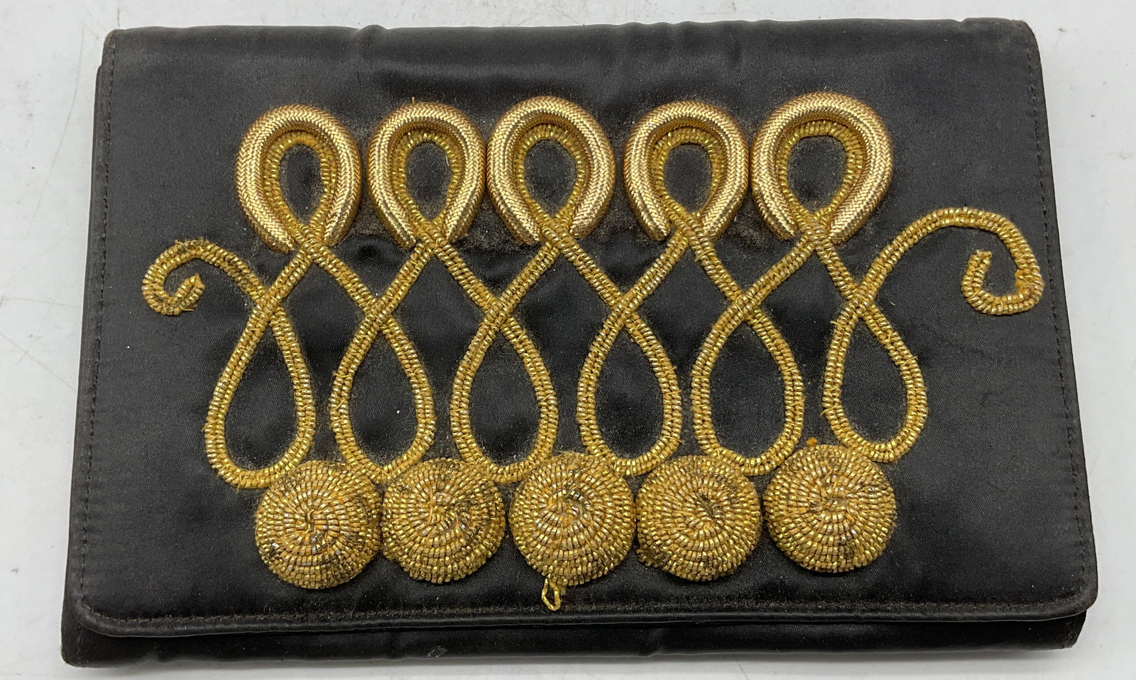 Tina Wolf Black Embroidered Folding Clutch Purse: Tina Wolf black embroidered folding clutch purse. Satin material. Gilt embroidered loop pattern. Embroidered ball design. Opens to fitted compartments. Measures approx 5 x 8 inches. Surface wear consi