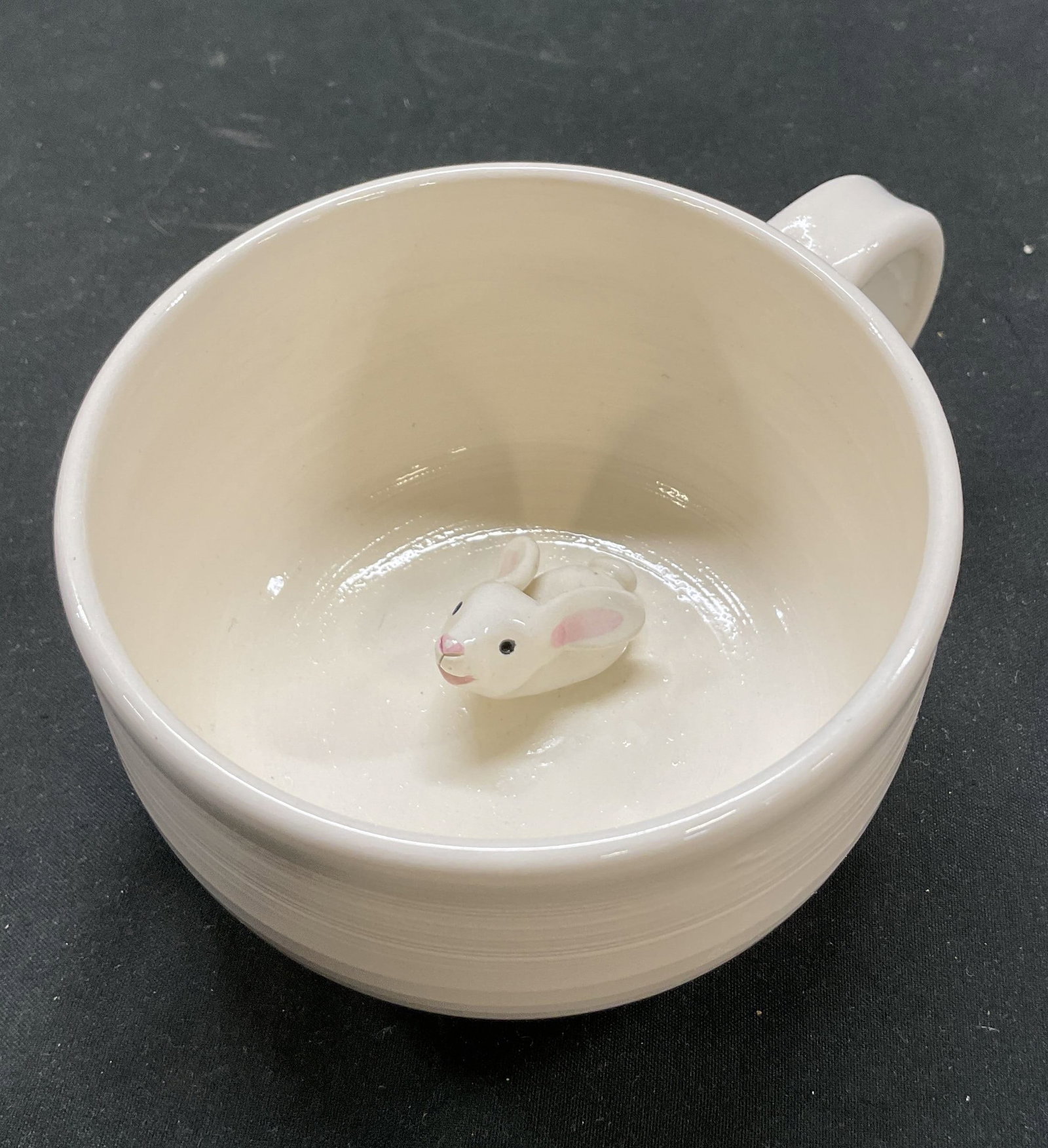 SGND Hand Made Ceramic Bunny Mug: Hand made ceramic bunny mug. Signed on underside. White round mug with curved handle. Hand painted bunny figure on inside. Measures approx 4 x 5.5 x 2.5 inches. Slight crazing. Mug, hand made mug, Eas