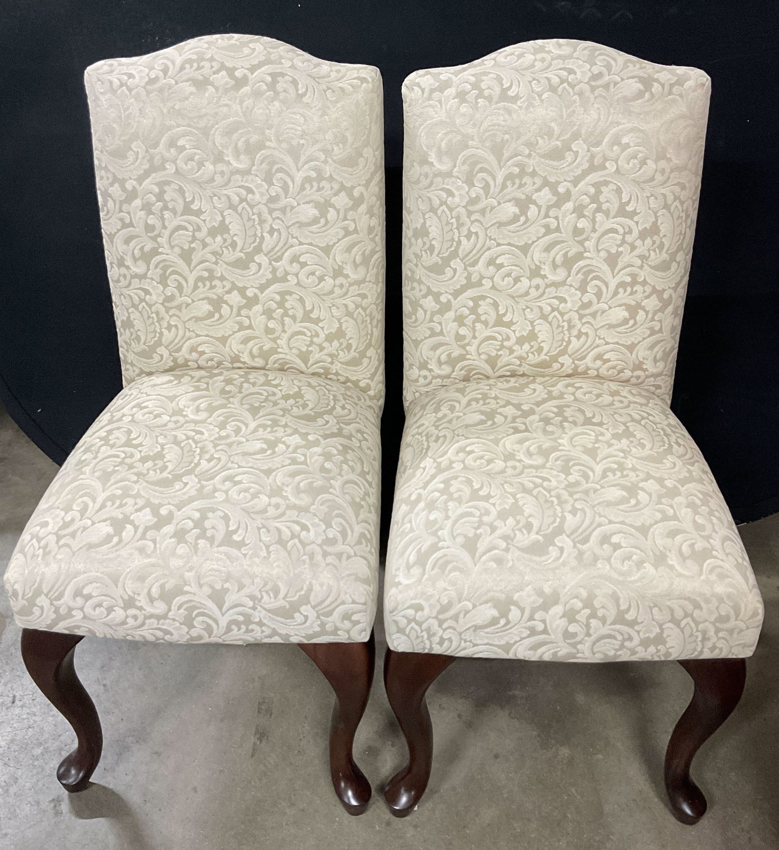 Pair 1993 Bombay Company Upholstered Chairs: Pair of The Bombay Company upholstered chairs. Marked on underside, dated 1993. Cream colored upholstered fabric seat and back. Scalloped design on top. Ornate scroll pattern. Armless dining chairs. C