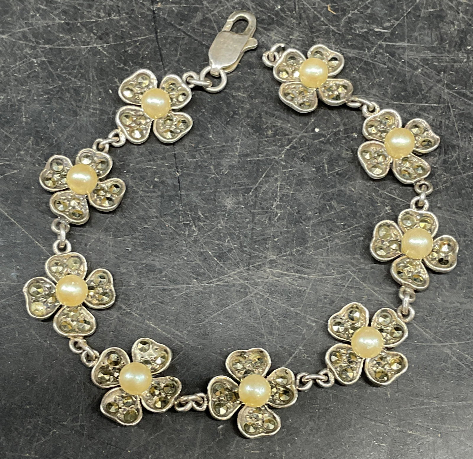 Vtg Sterling Silver Faux Pearl Flower Bracelet: Vintage sterling silver flower bracelet with faux pearls and marcasite measures approx. 7 inches long. Marked sterling. Total weight 17.5 grams. Some scratching. One faux pearl previous repaired, one