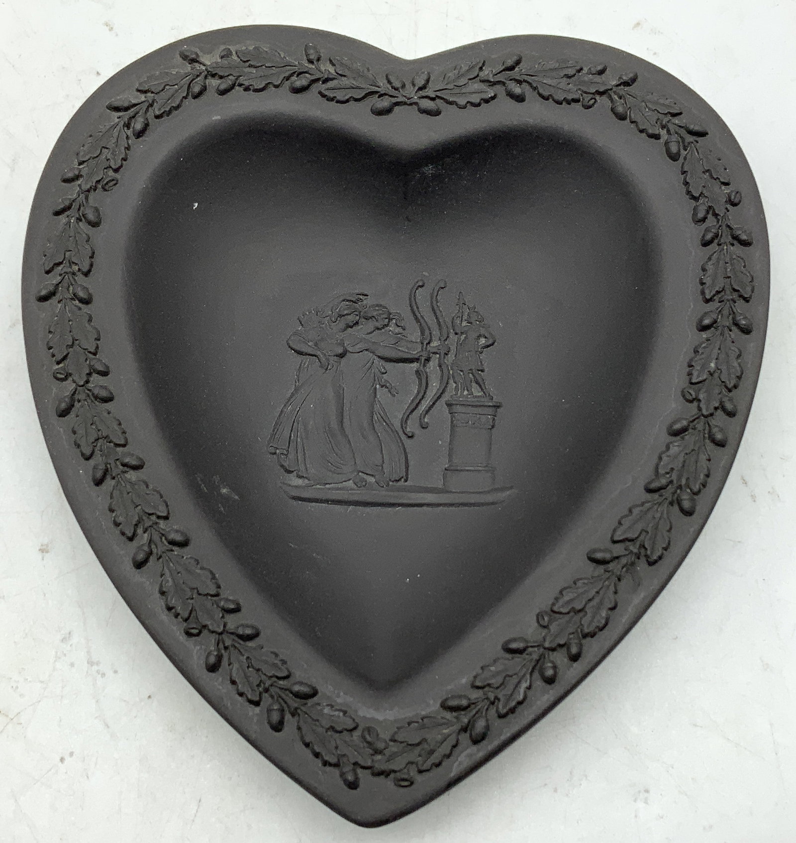 Wedgwood Black Jasperware Trinket Dish ENG: Wedgwood black Jasperware heart shaped trinket dish features a neoclassical relief in center & leaf border. Signed & marked on underside. Reads, WEDGWOOD MADE IN ENGLAND. Surface wear consistent to ag