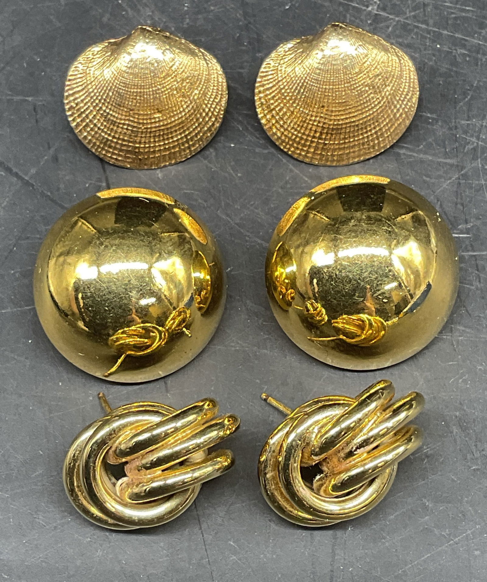Lot 3 Gold Tone Shell, Knot Stud Earrings: Lot of 3 pairs of earrings. Gold tone shell, knot, and stud. Largest measures approx. .75 inches wide. Some scratching. Jewelry, estate jewelry, costume jewelry, cocktail jewelry, fashion jewelry,