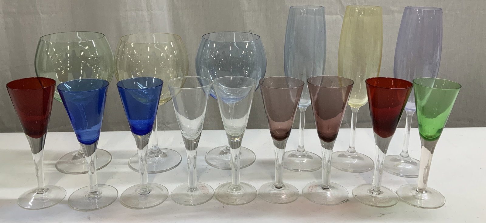 Lot 15 Assorted Colorful Glass & Crystal Stemware: Lot includes, 3 champagne flutes, 3 wine glasses & 9 hand blown crystal glasses. Crystal & glass. Assorted sizes & shapes. Red, clear, blue, purple, green & yellow. Round base. Surface wear consistent
