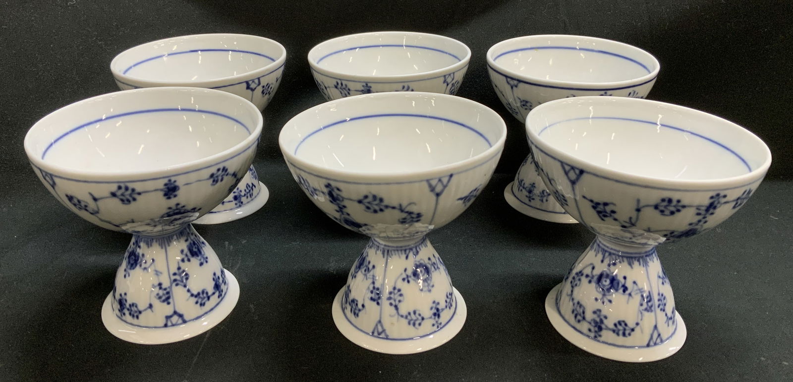 Set 6 Royal Copenhagen Footed Bwl DENMARK: Lot includes, set 6 porcelain footed bowl featuring classic blue & white floral motifs. Glossy finish. Blue rim in interior. Signed & marked on underside. Reads, DENMARK. KRX. Appears to be possible R